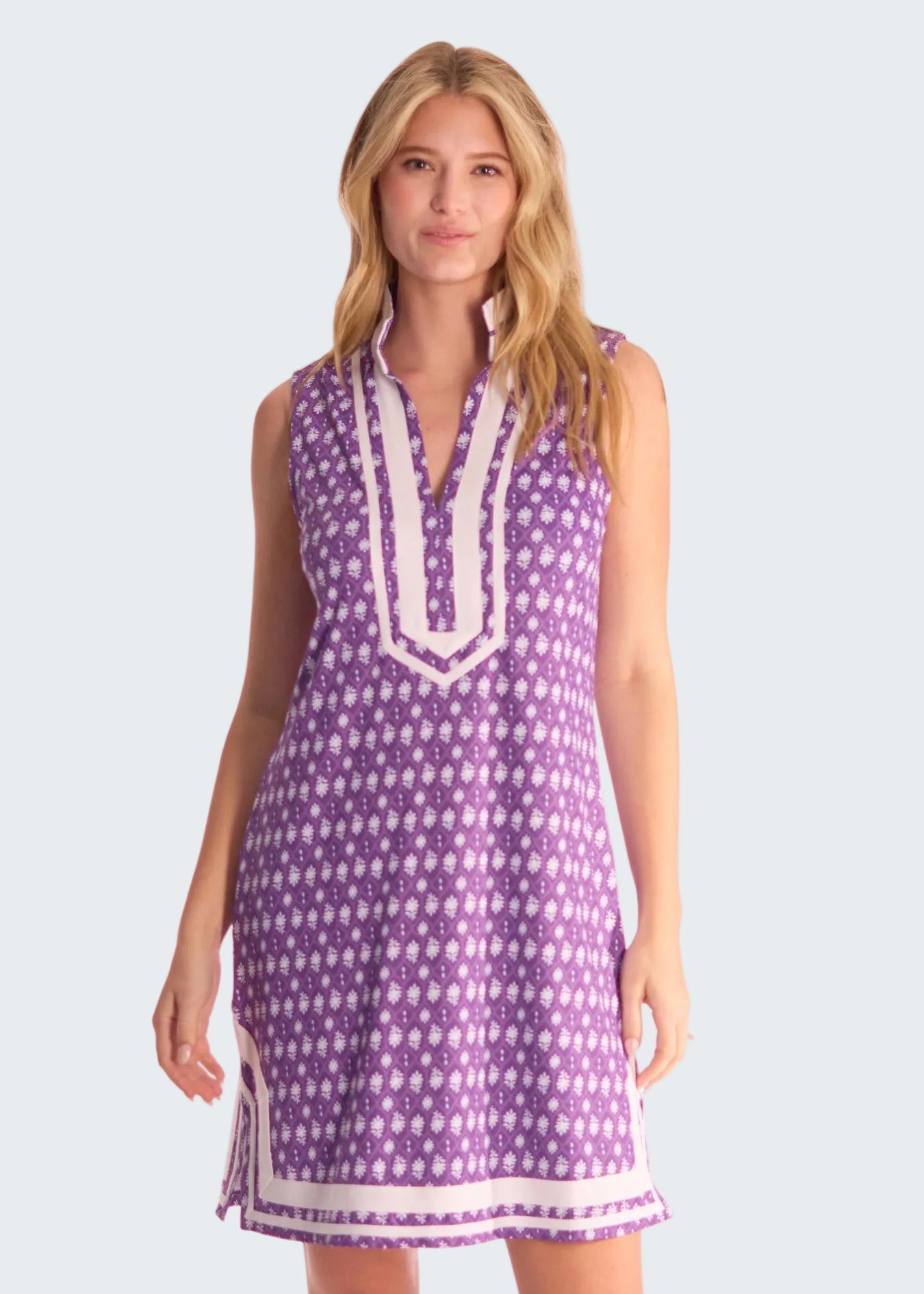 Woman wearing a purple patterned dress with white trim on a white background
