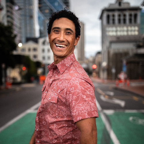 Man in a red patterned shirt standing on a city street