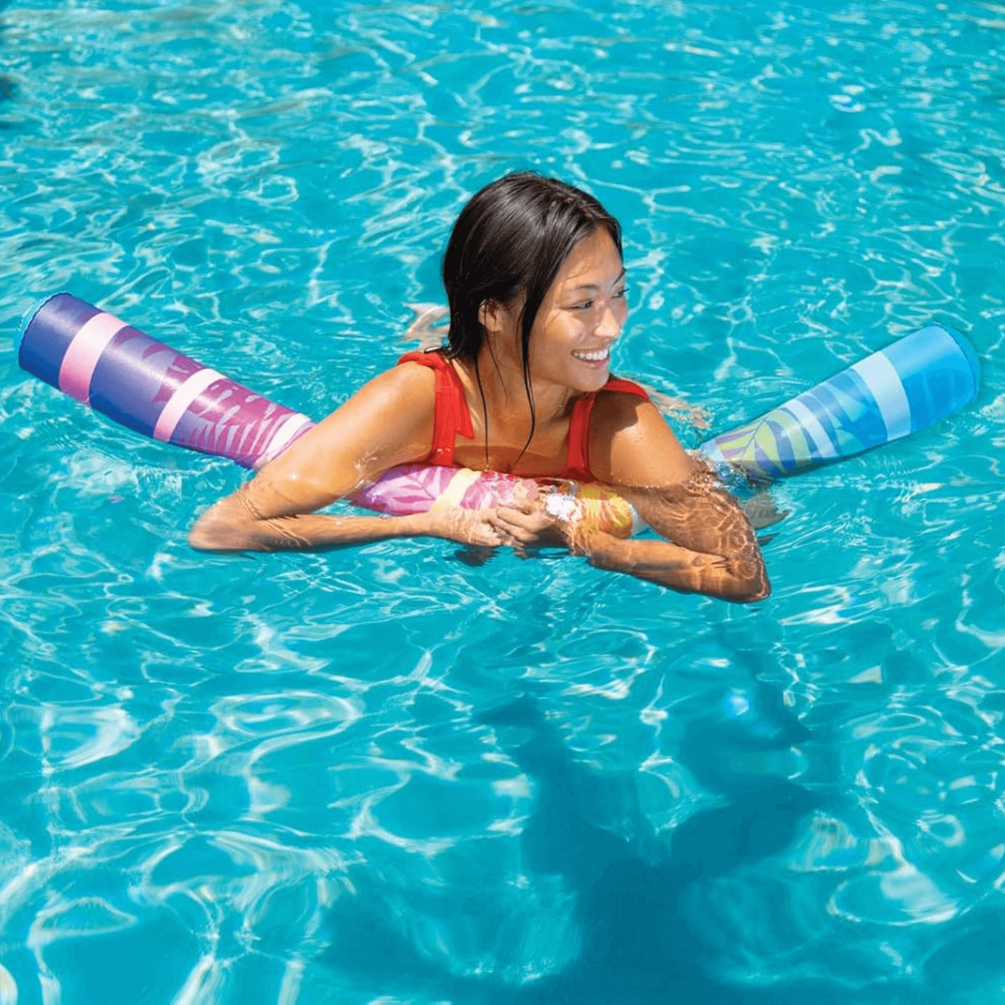 Woman in a pool with colorful pool noodles and a pink life jacket