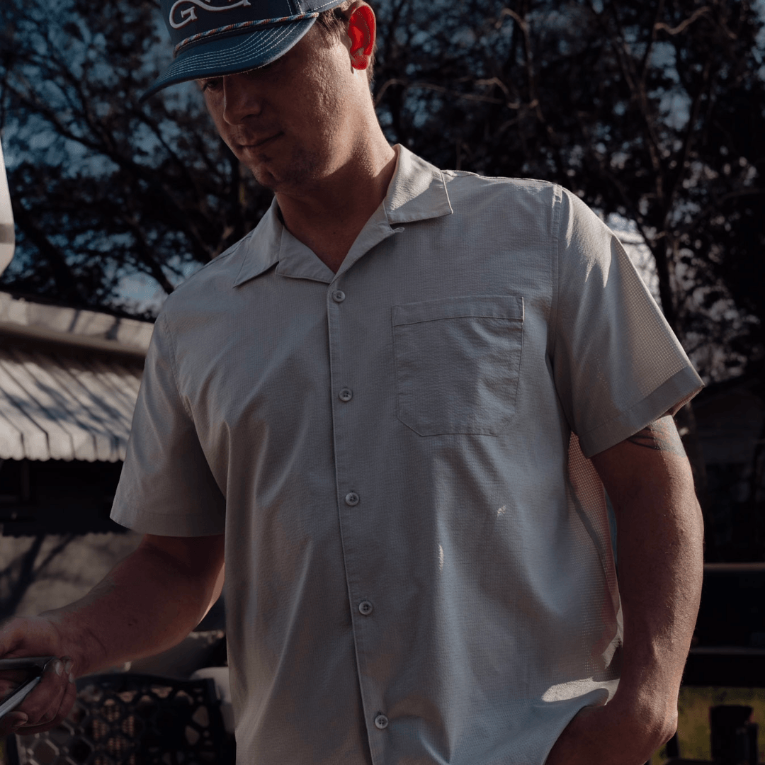 Man wearing a light gray shirt and blue cap outdoors