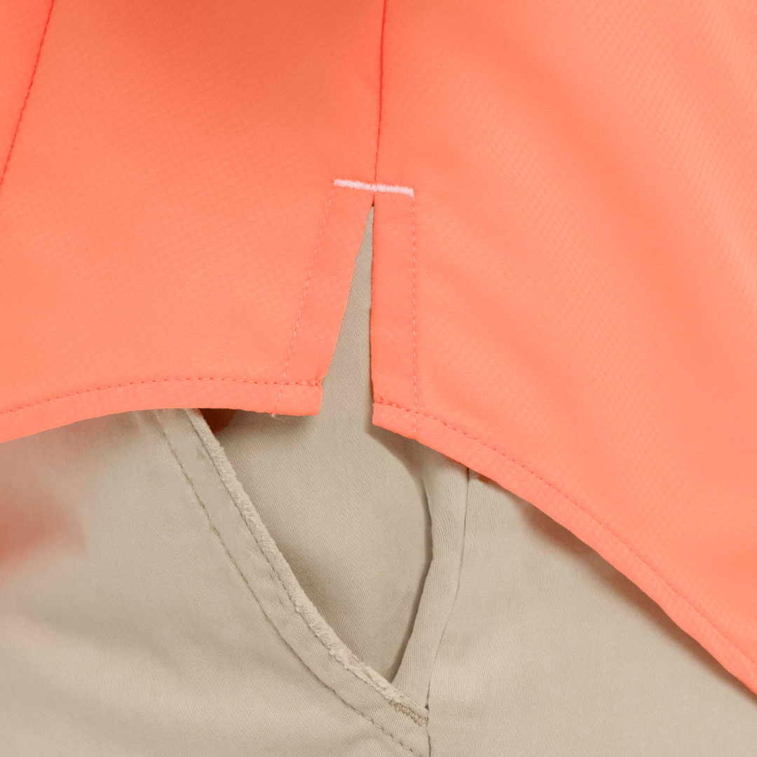Close-up of a coral shirt and beige pants with a visible brand label.
