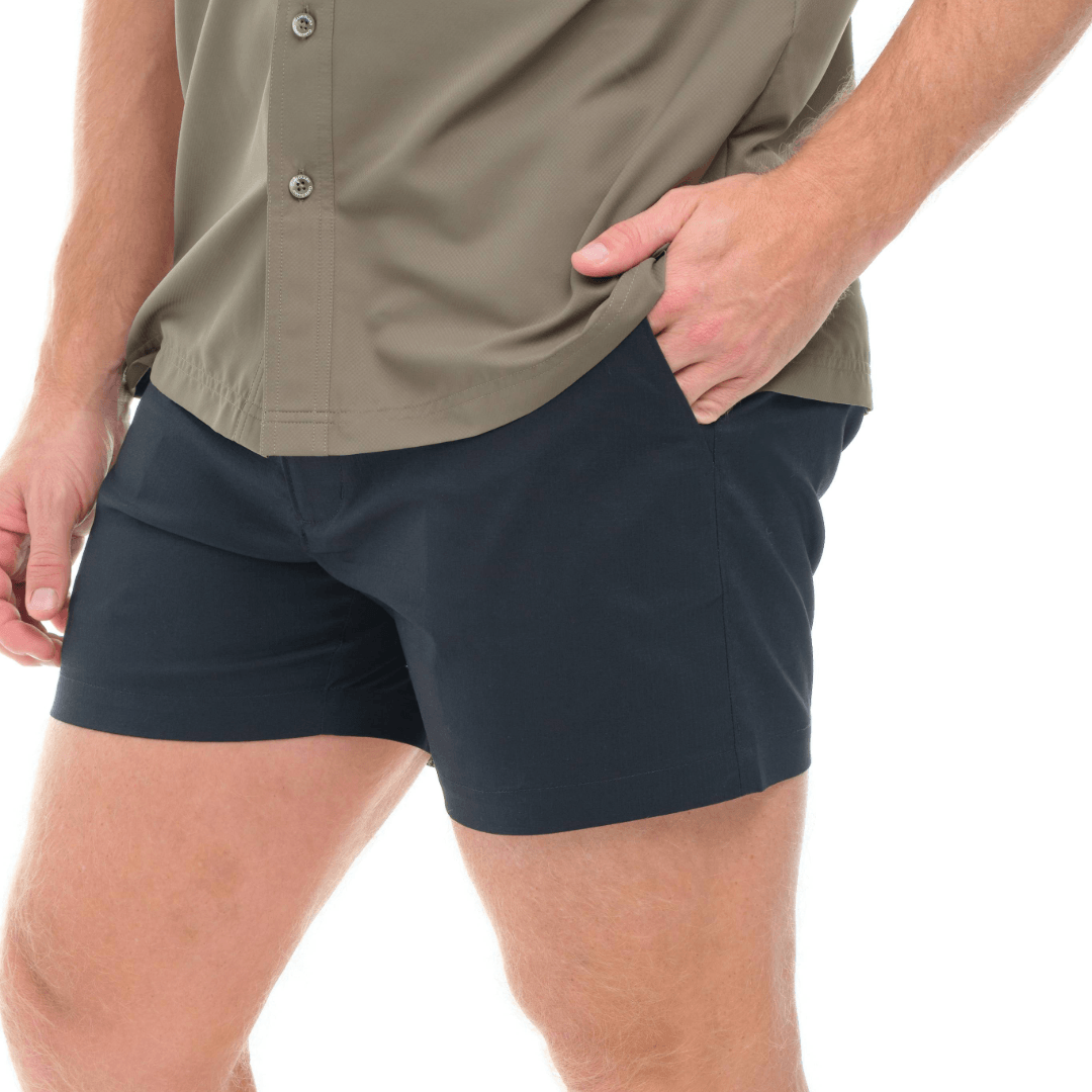 Person wearing navy shorts and a beige shirt on a white background