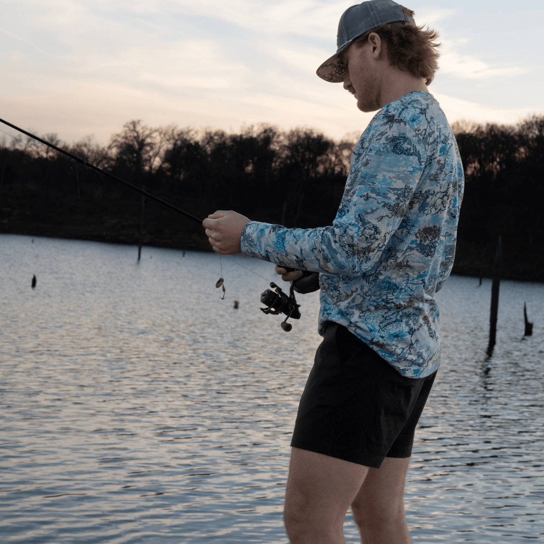 Man fishing by a lake at sunset