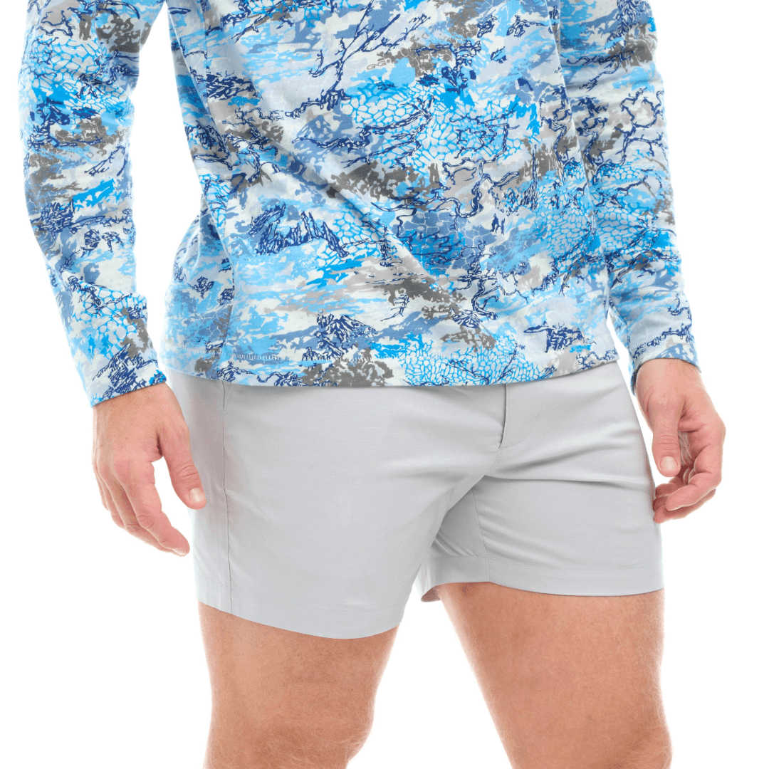 Person wearing a blue and gray camouflage long-sleeve shirt and light gray shorts on a white background