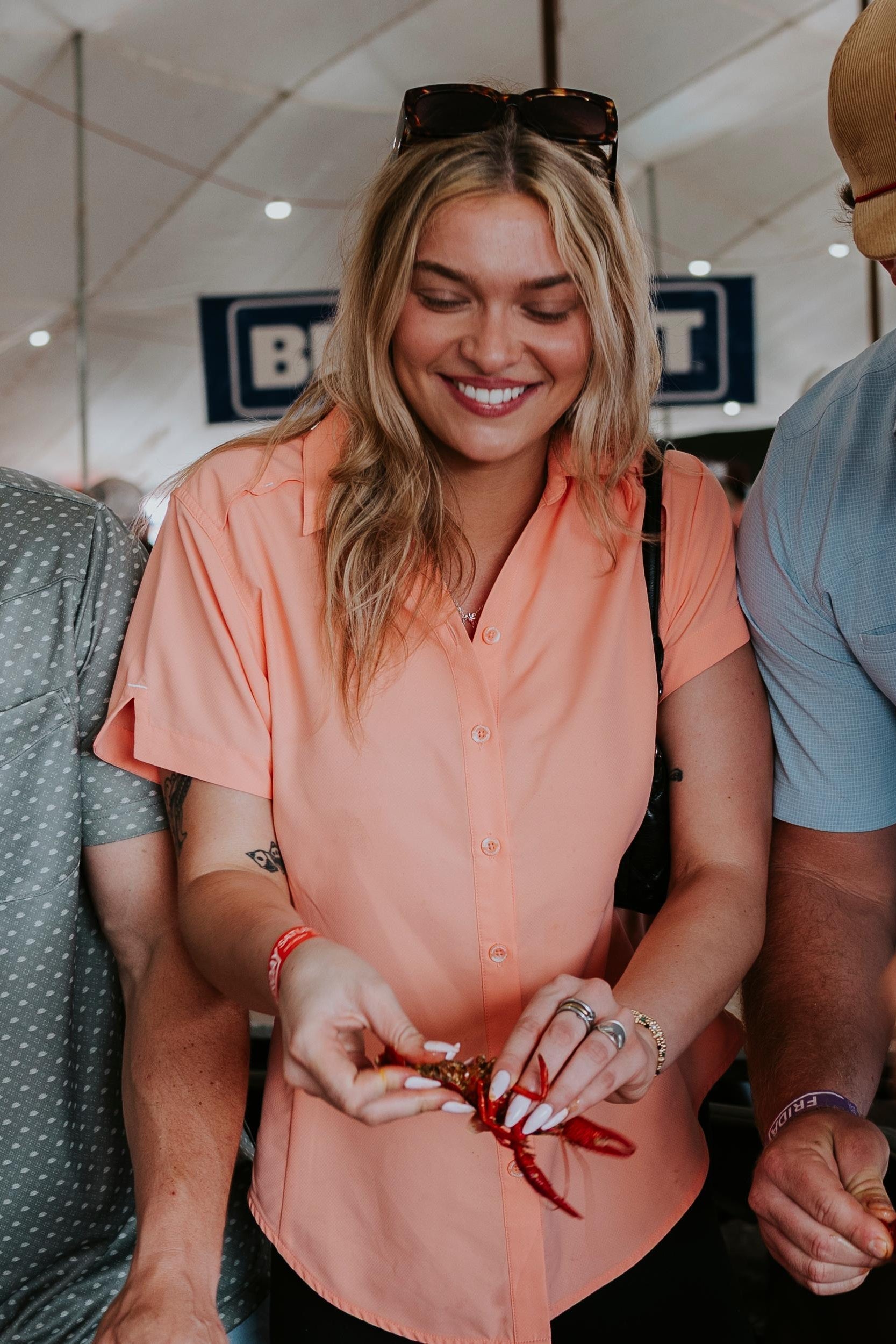 Woman in peach shirt holding a red object with people around her.