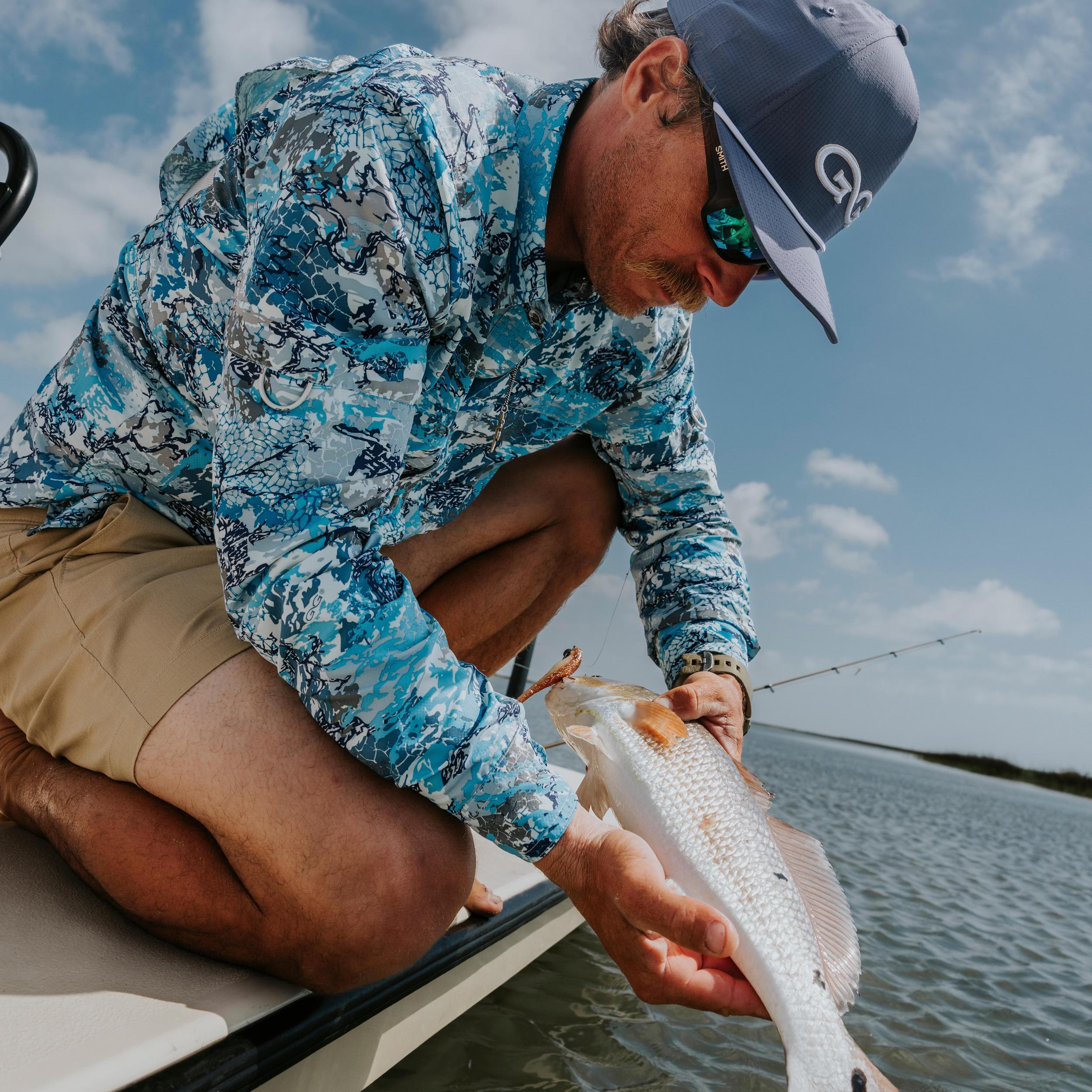Man on a boat holding a fish with a blue sky and water background