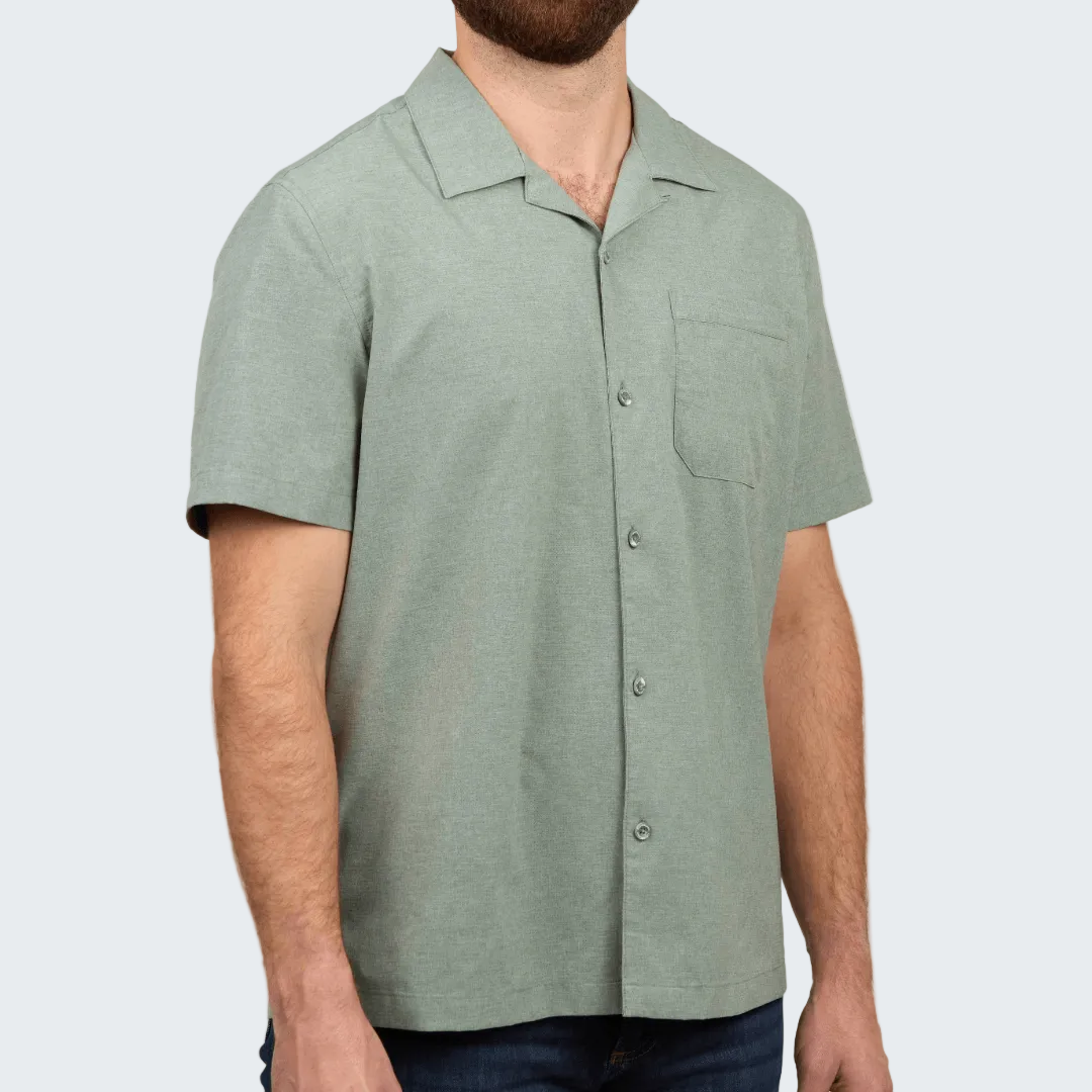 Man wearing a green short-sleeve button-up shirt on a white background