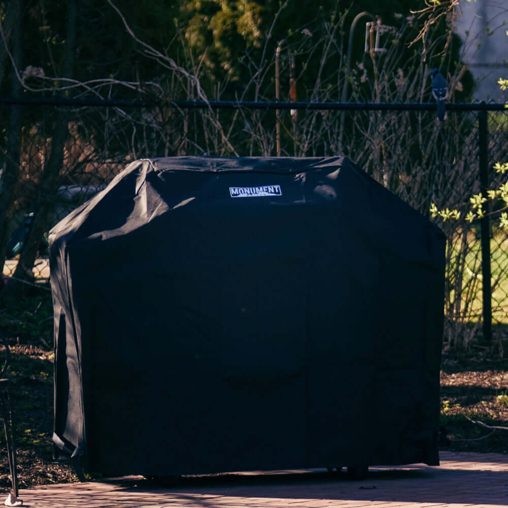 Black grill cover with 'Monument' branding on a patio