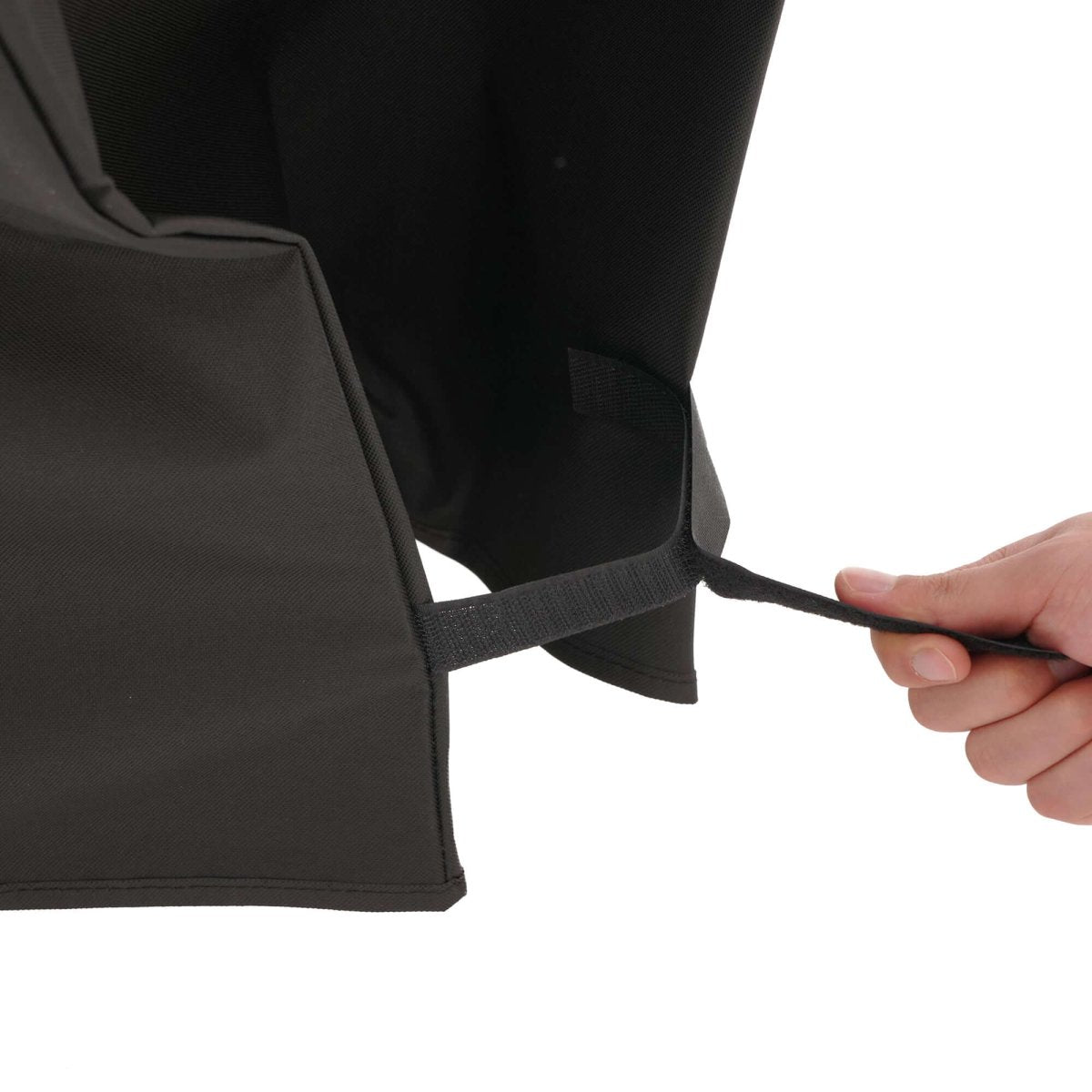 Person holding a black bag with a strap on a white background
