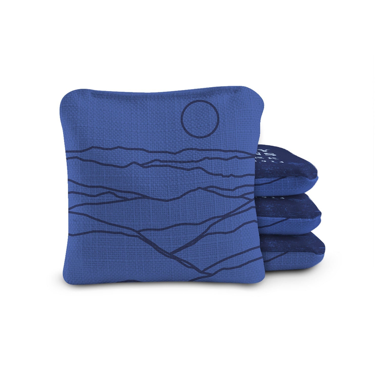 Blue cornhole bags with mountain and moon design on a white background