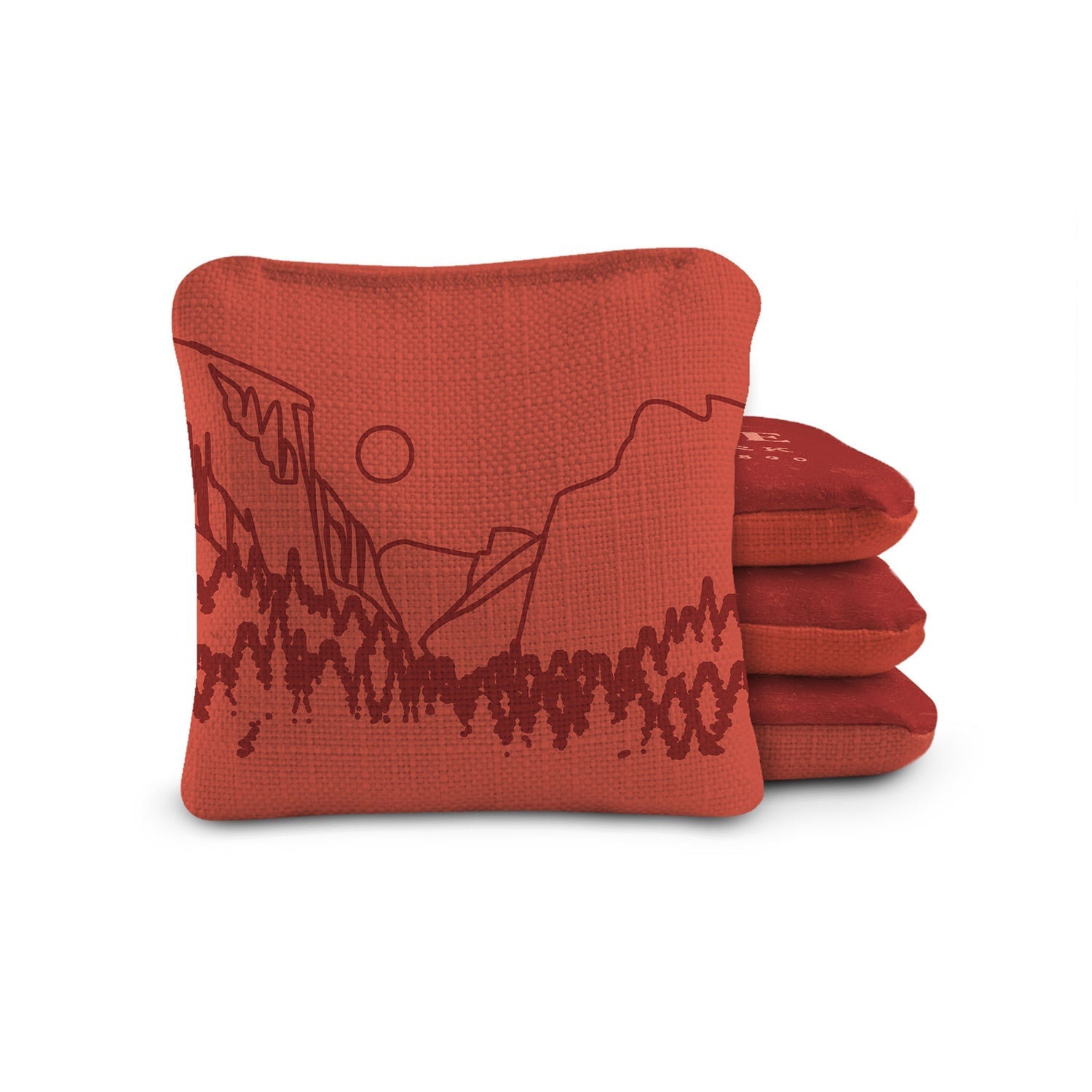 Red cornhole bags with mountain design on a white background
