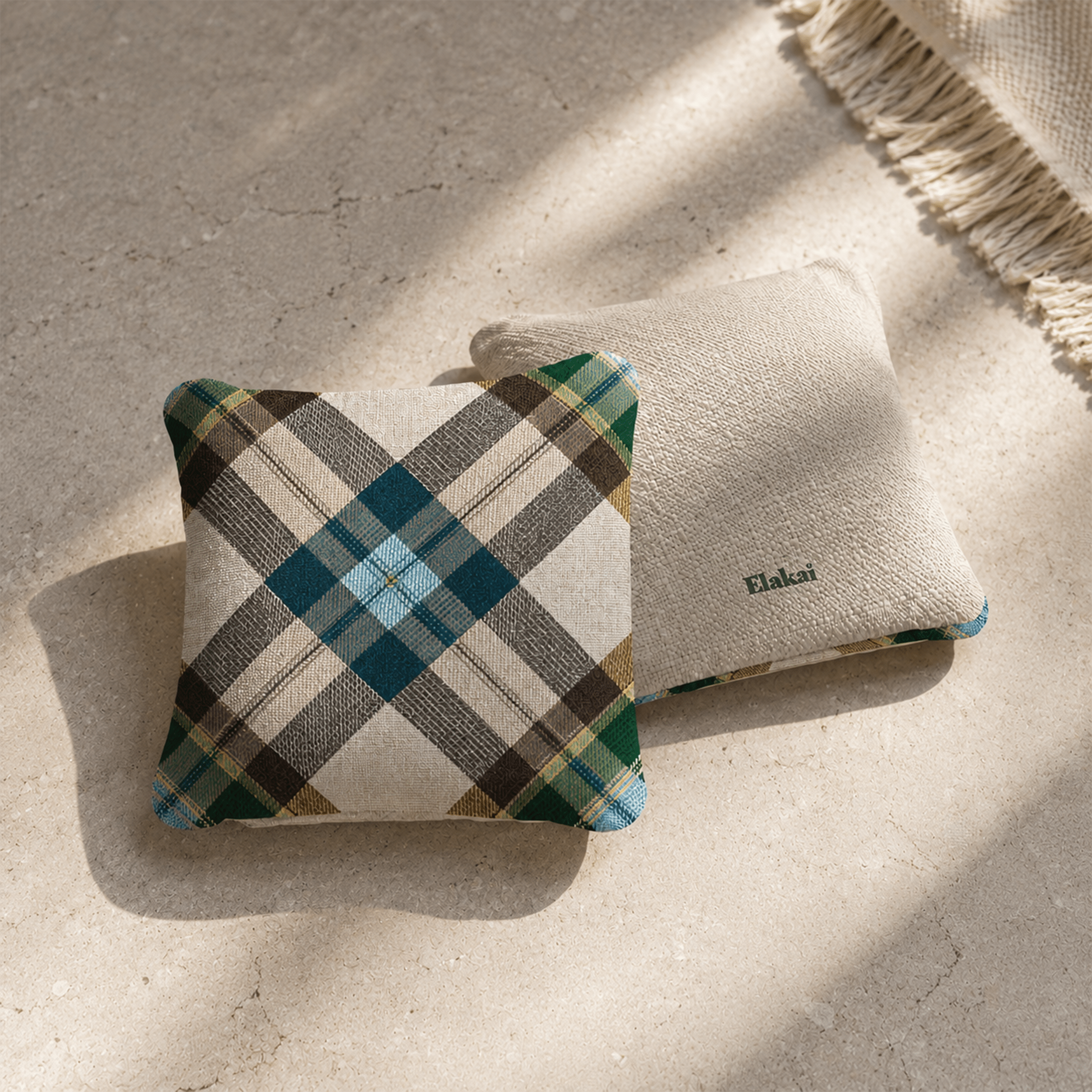 Two decorative pillows on a textured surface, one plaid and one plain.