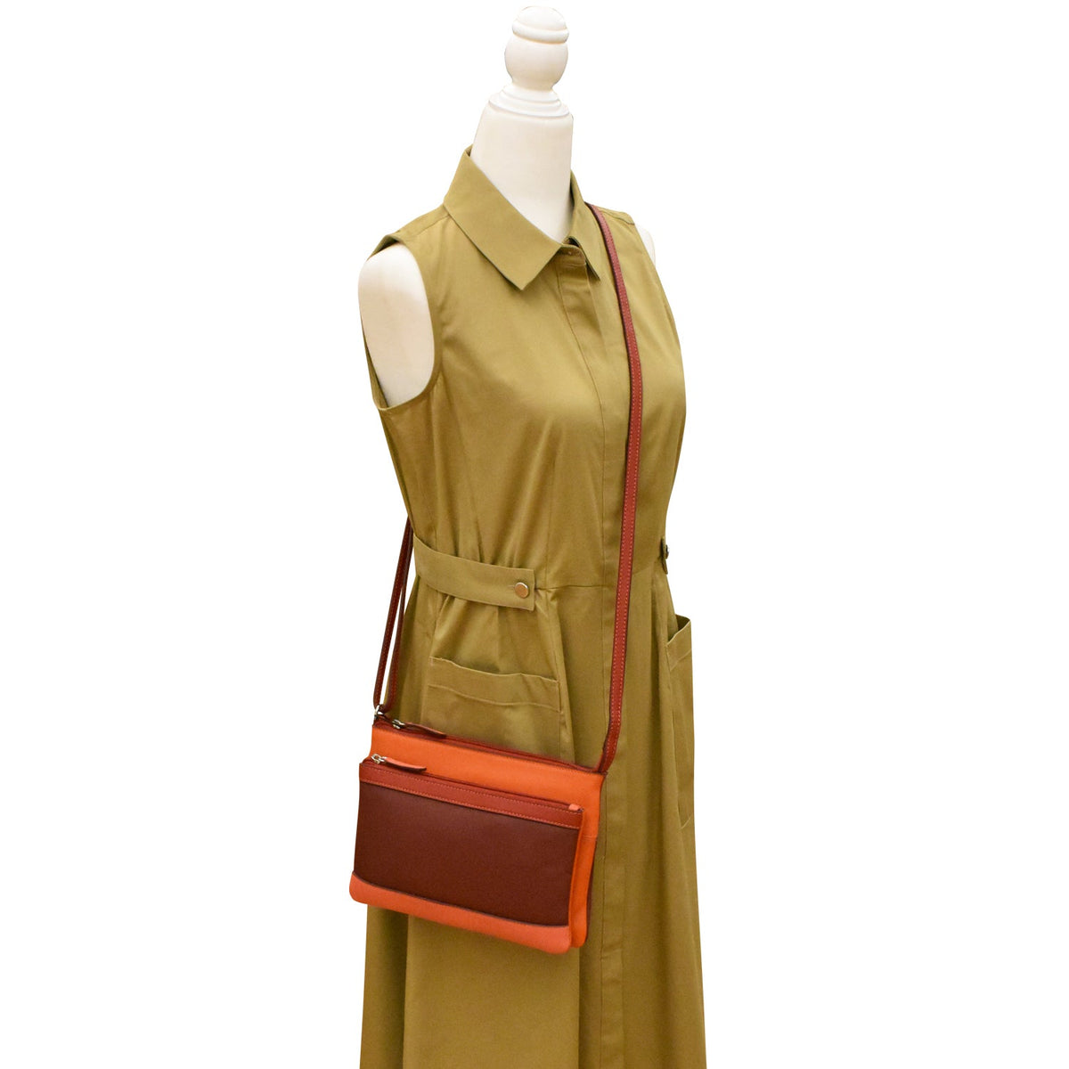Mannequin wearing a green dress with an orange and brown crossbody bag on a white background