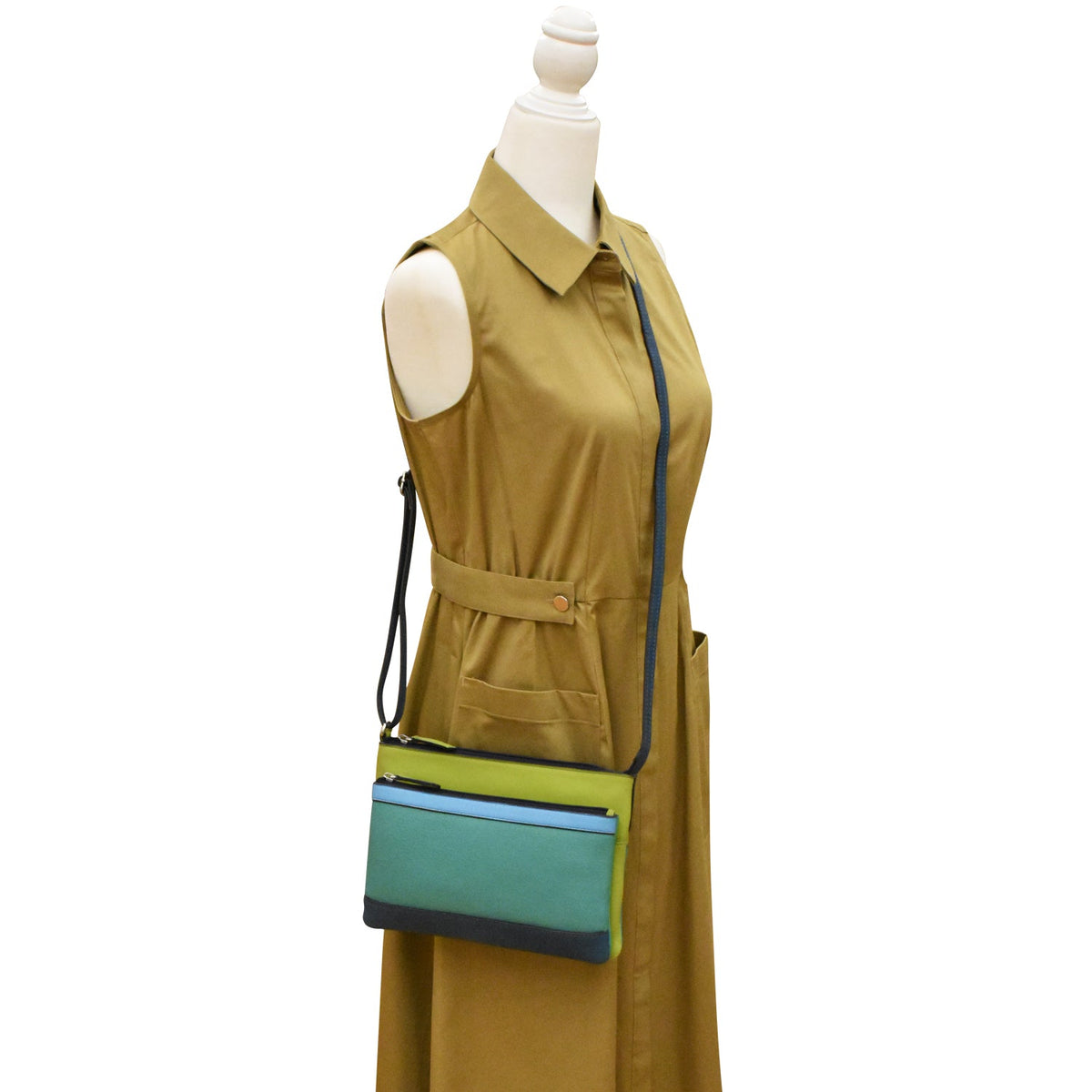 Mannequin wearing a mustard yellow dress with a green and blue bag on a white background