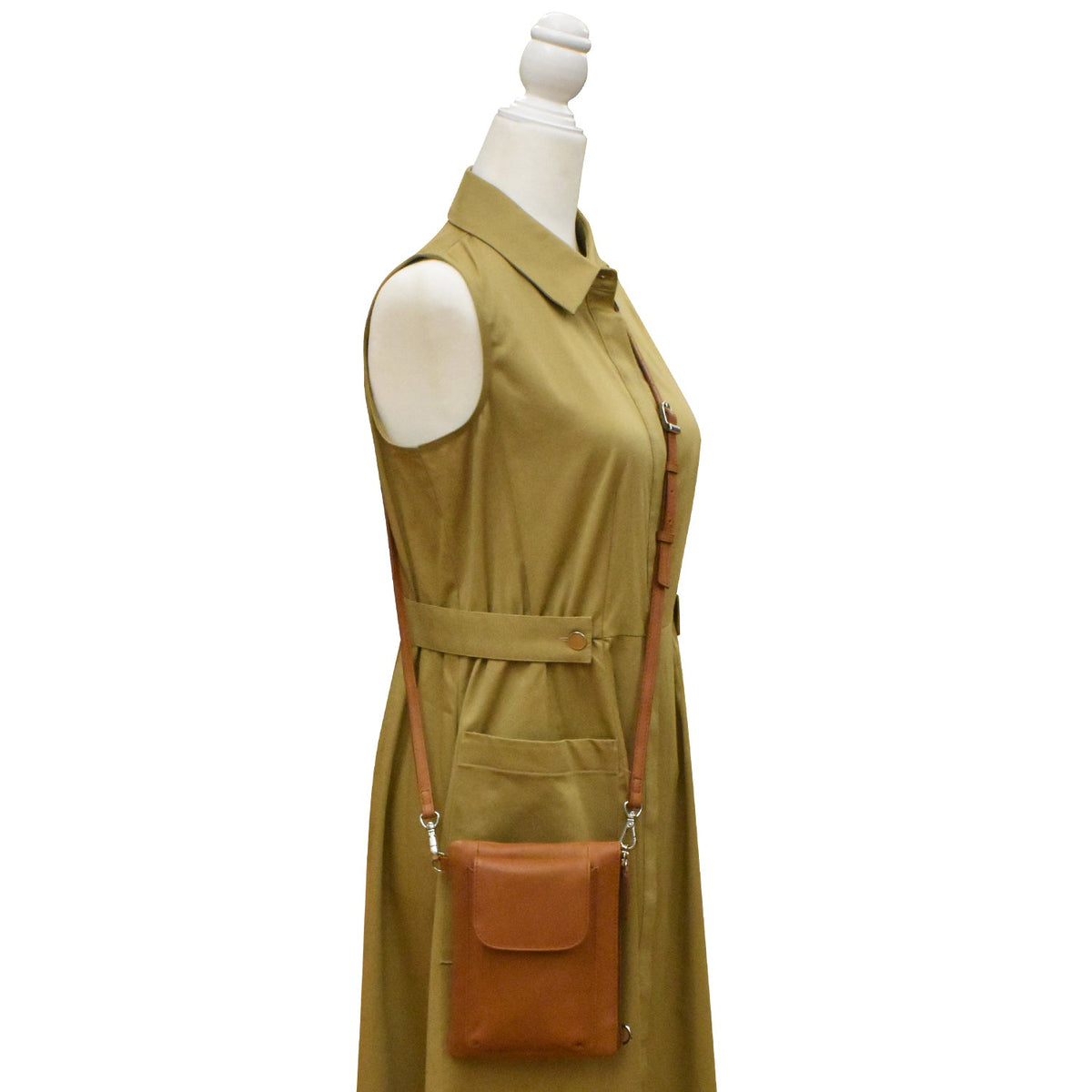 Green dress with brown crossbody bag on a mannequin against a white background