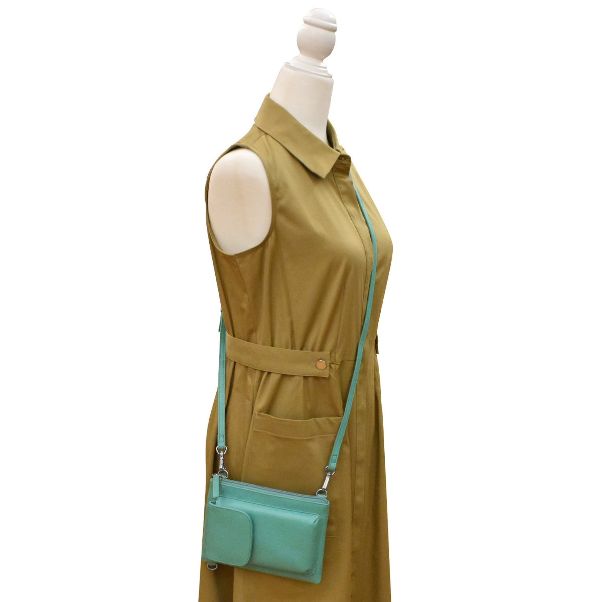Mannequin wearing a brown dress with a matching green handbag on a white background