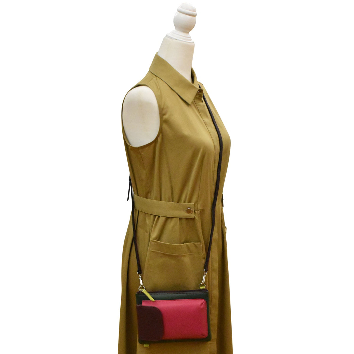 Mannequin wearing a beige sleeveless dress with a red and black handbag.