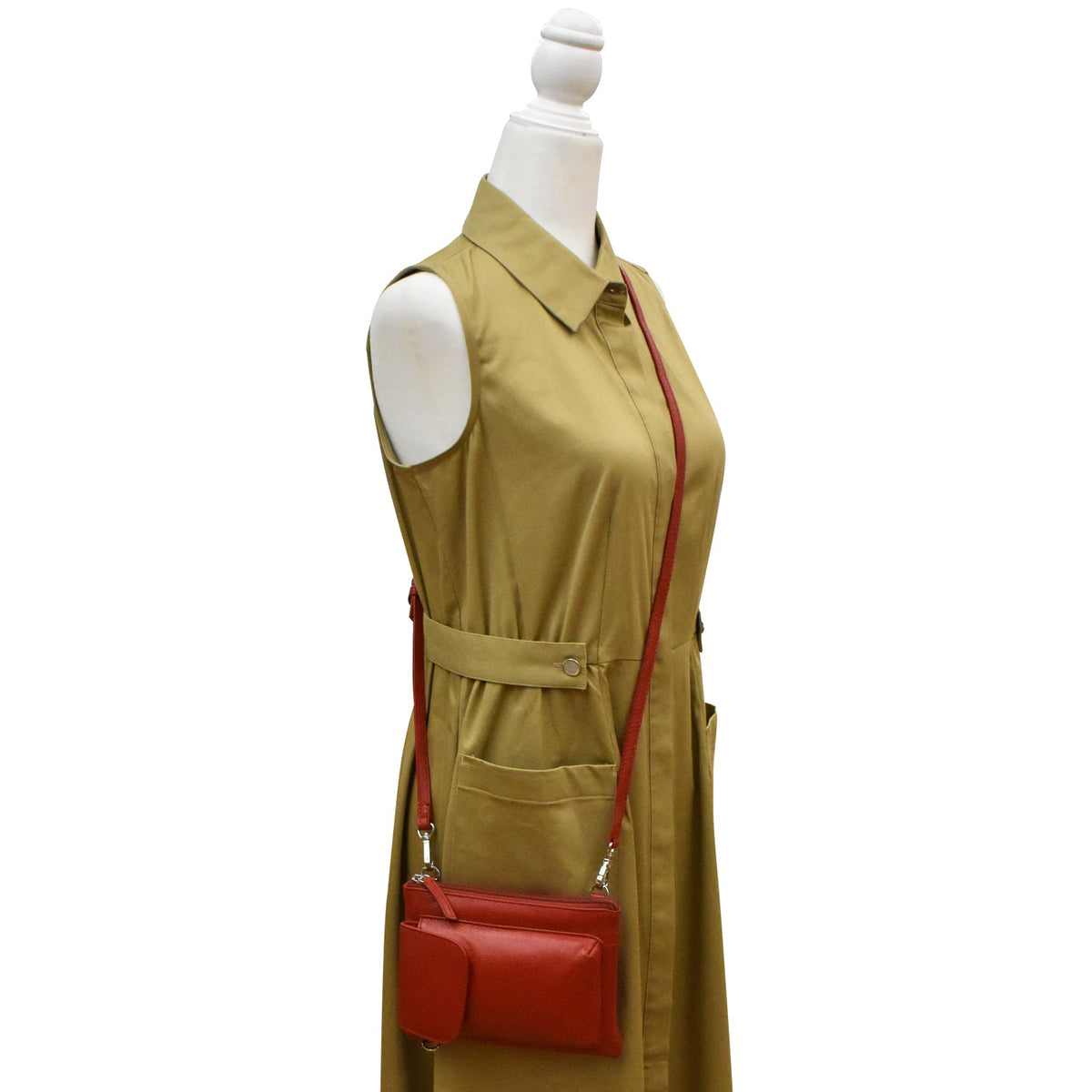 Mannequin wearing a beige dress with a red handbag on a white background