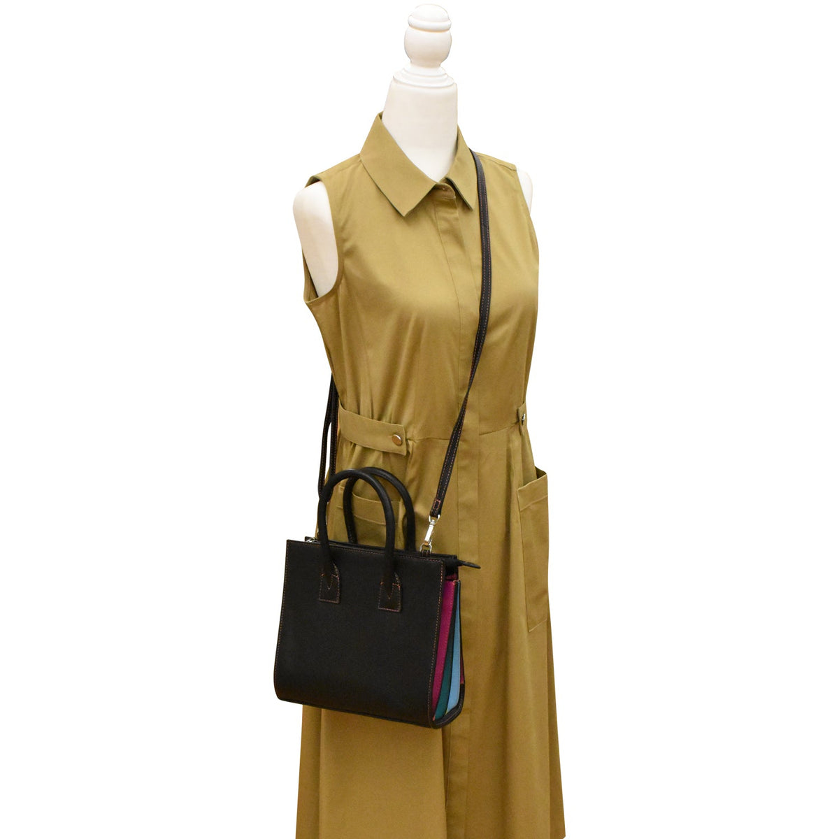 Mannequin wearing a mustard yellow dress with a black handbag on a white background