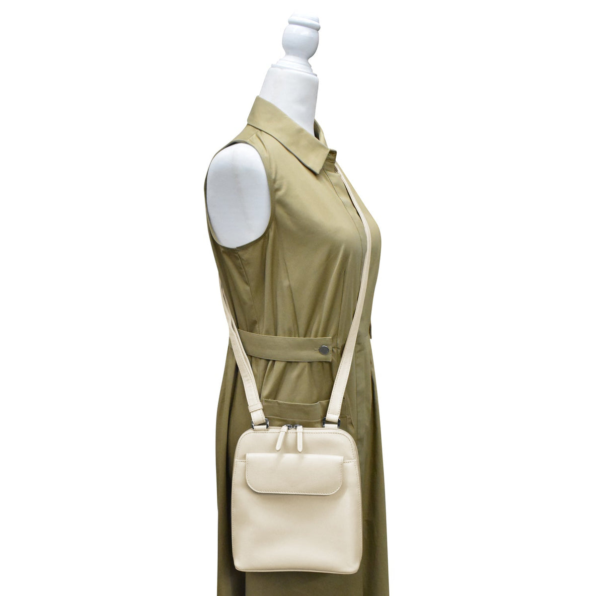 Mannequin wearing a green dress with a beige crossbody bag on a white background