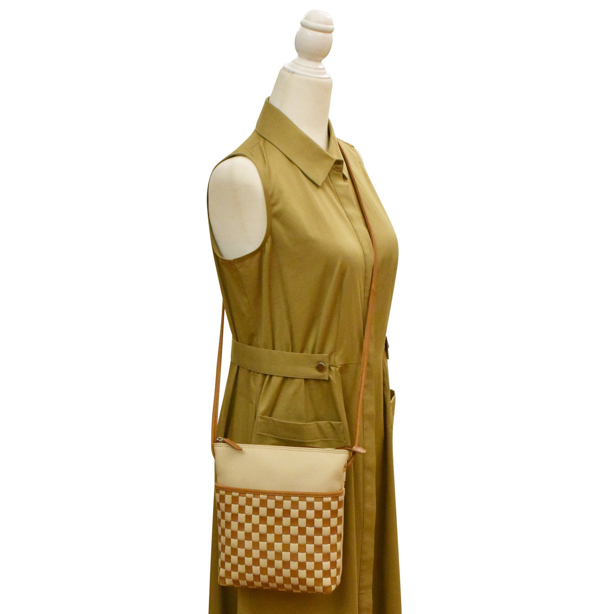 Green sleeveless dress with a matching checkered bag on a mannequin against a white background