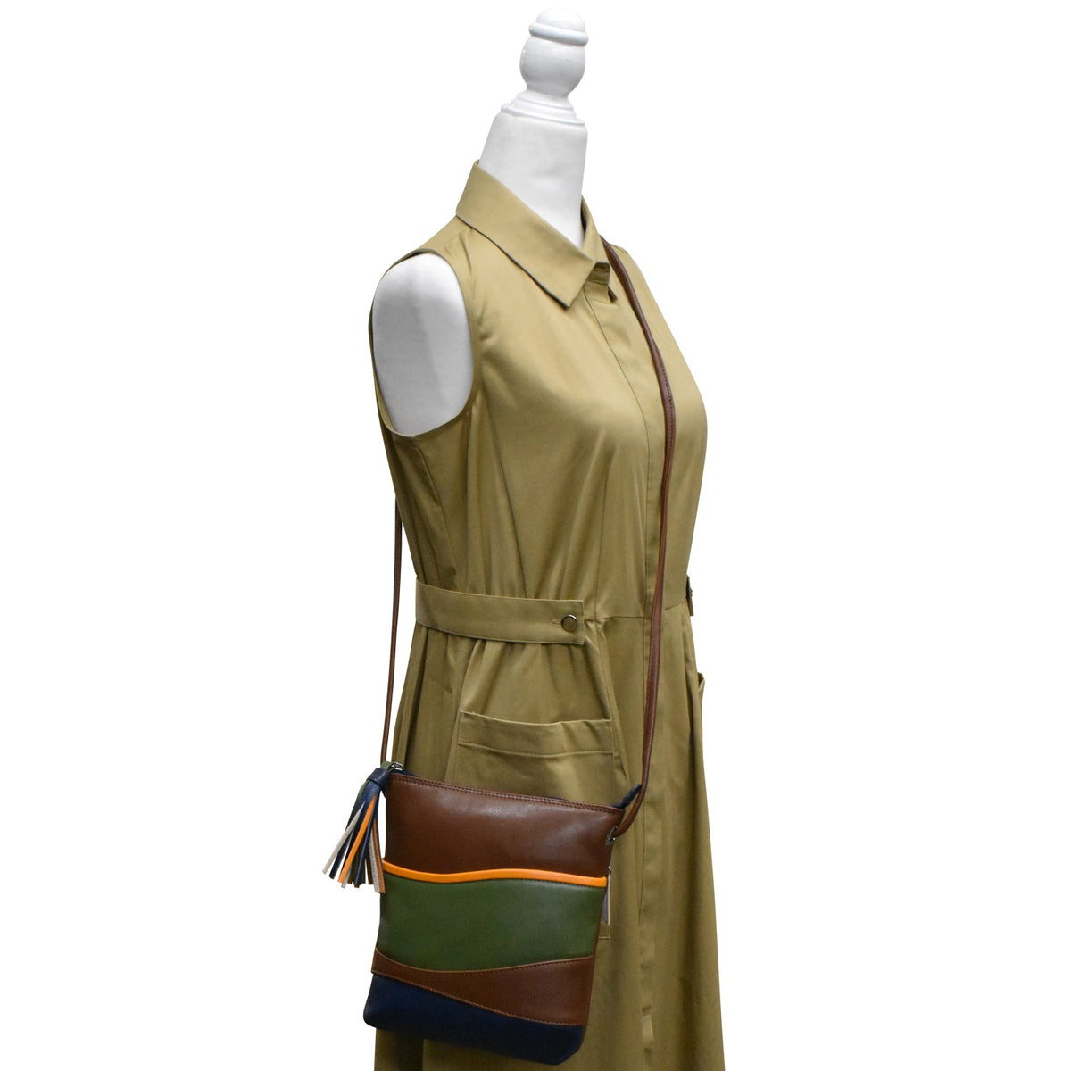 Mannequin wearing a beige dress with a brown and green handbag on a white background