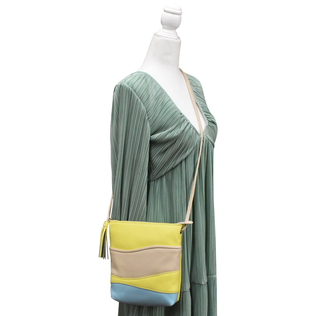 Green dress with a multicolored handbag on a mannequin against a white background