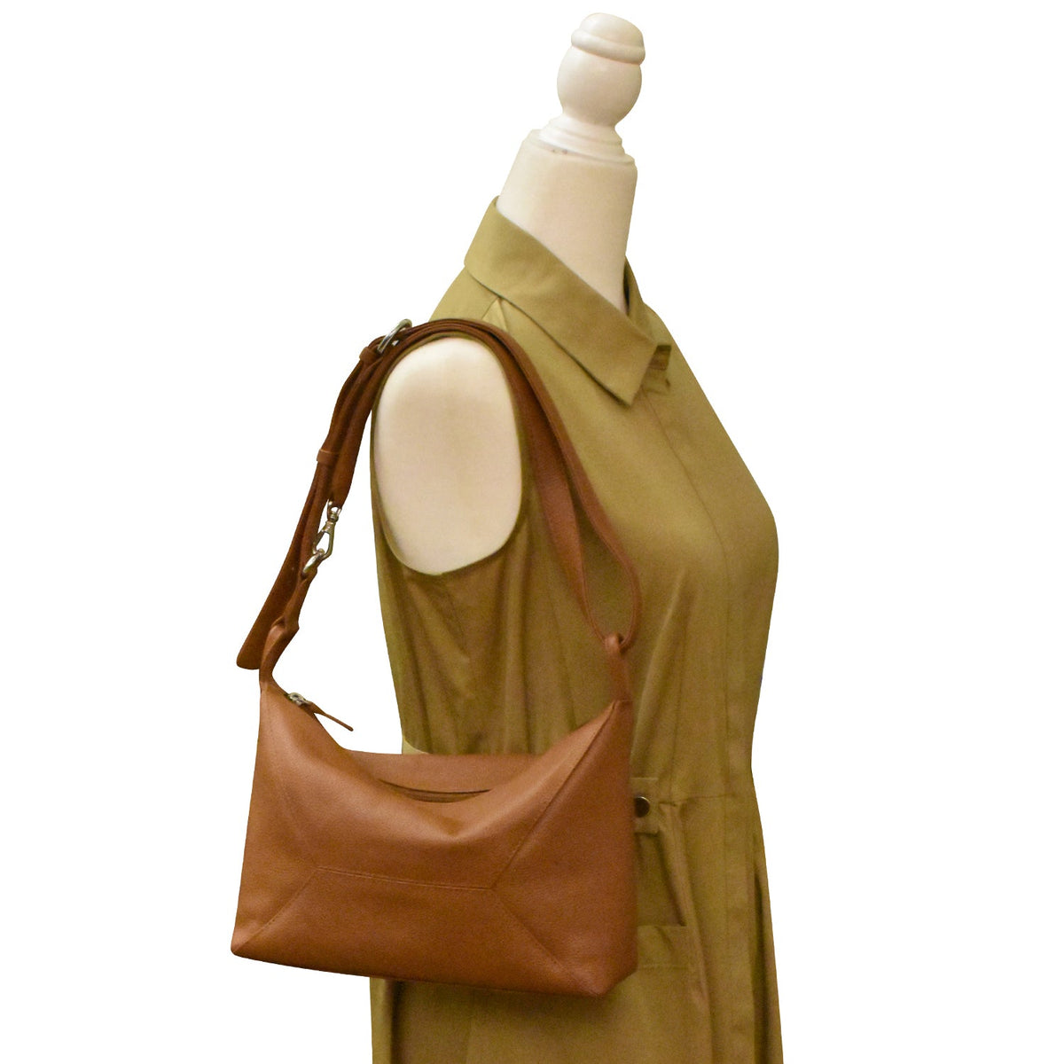 Brown leather handbag worn by a mannequin against a white background