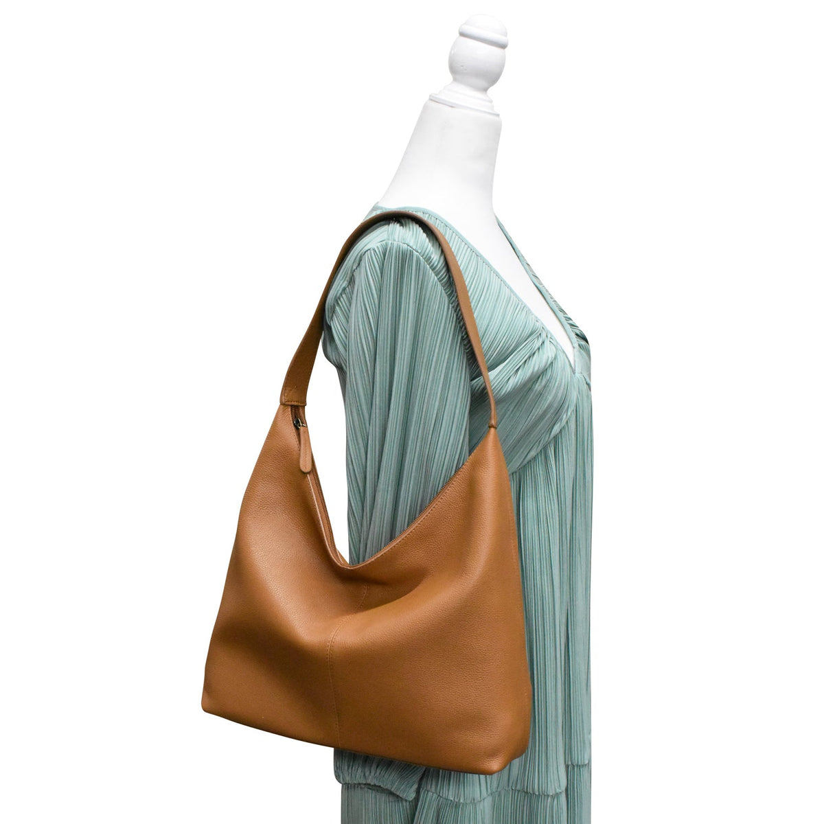 Brown leather handbag on a mannequin with a light green dress against a white background