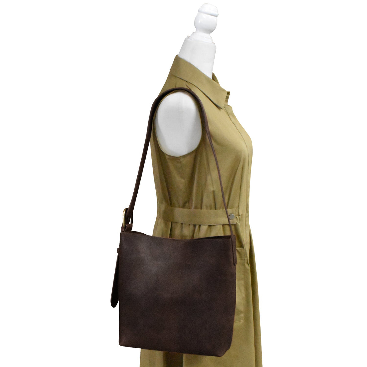Brown leather handbag on a mannequin wearing a beige dress against a white background
