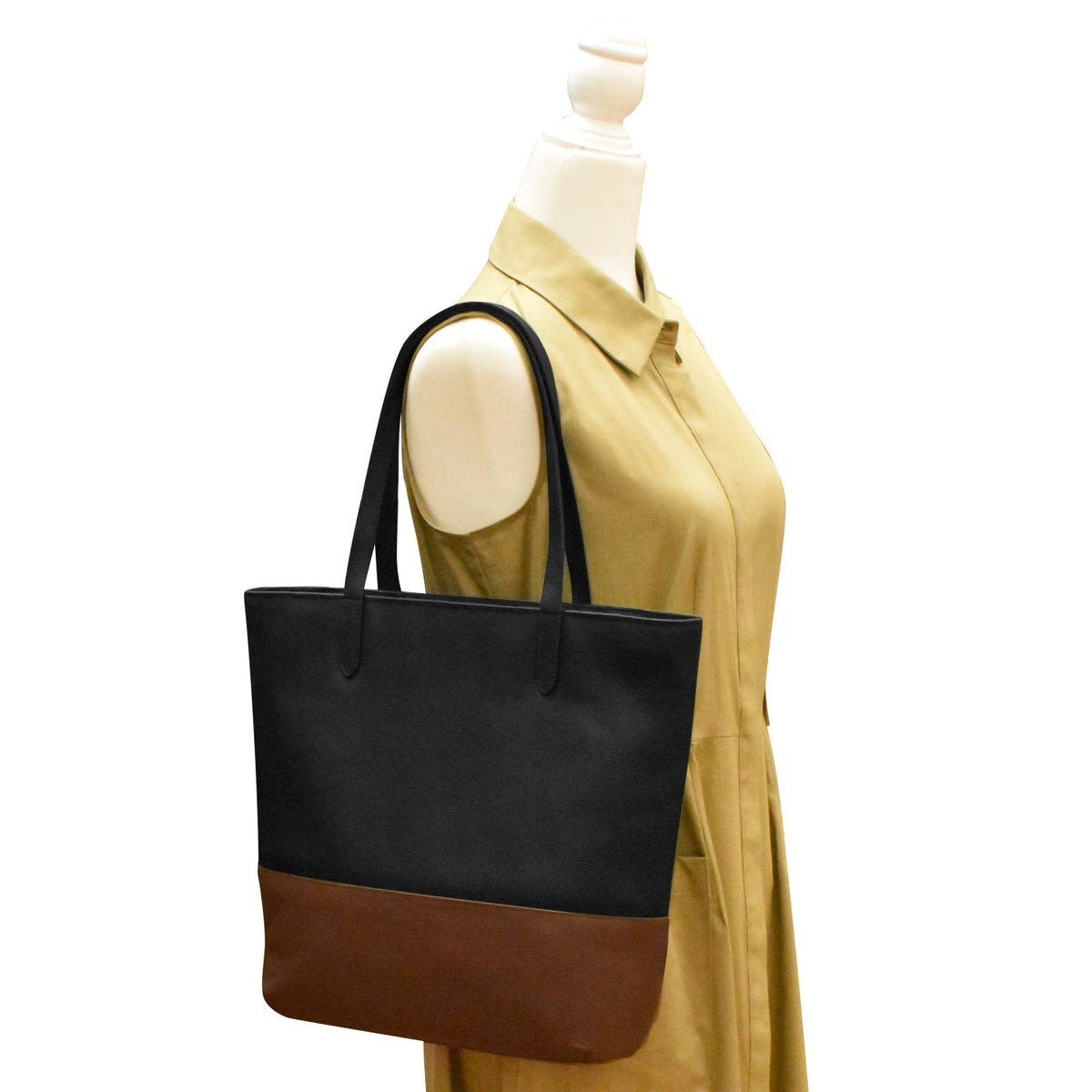 Black and brown tote bag on a mannequin with a yellow shirt against a white background