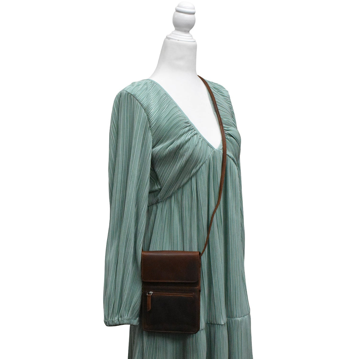 Green pleated dress with a brown crossbody bag on a mannequin against a white background