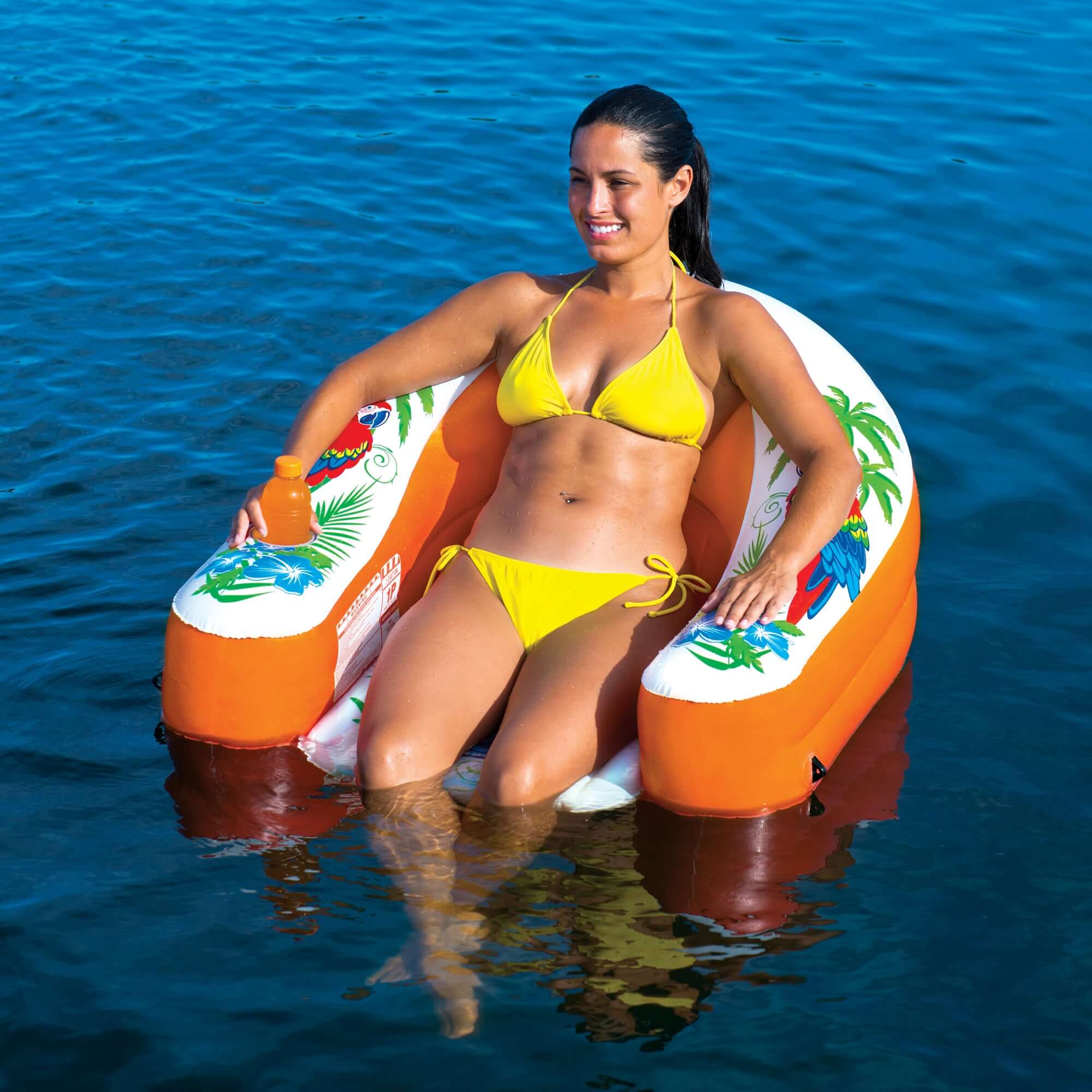 Woman in yellow bikini sitting on an inflatable tube with a colorful design in the water.