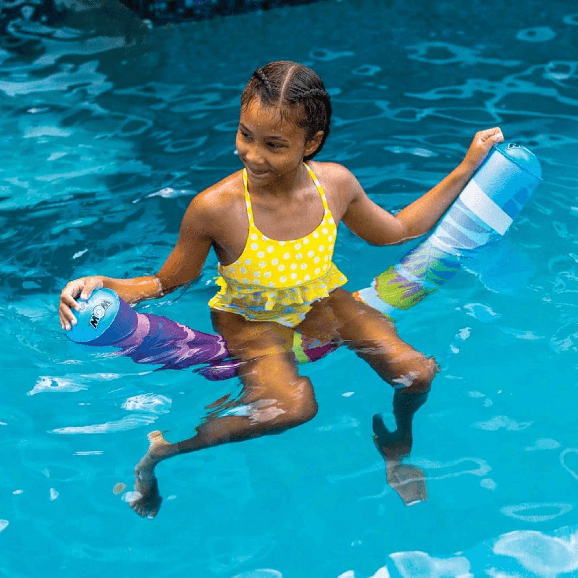 Child in a yellow swimsuit holding a colorful toy in a pool