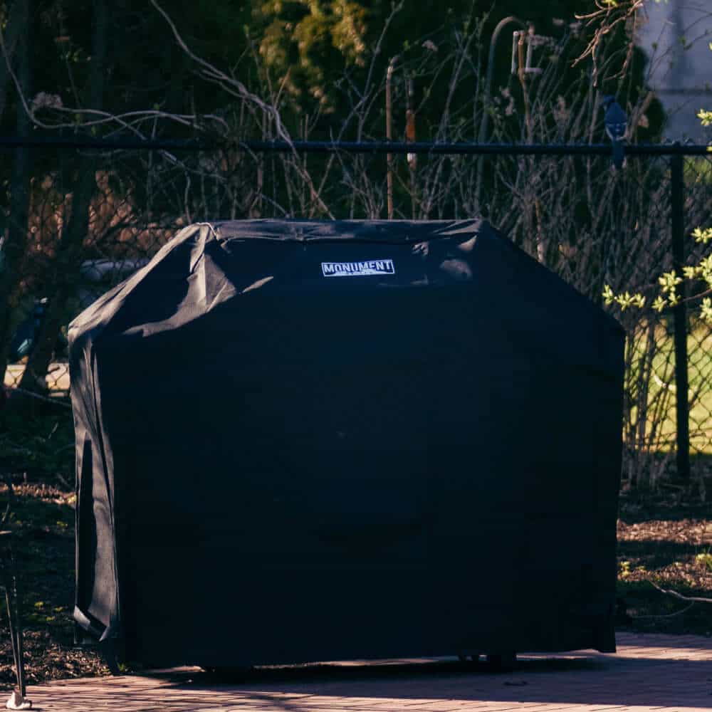 Black grill cover with a brand logo on a patio