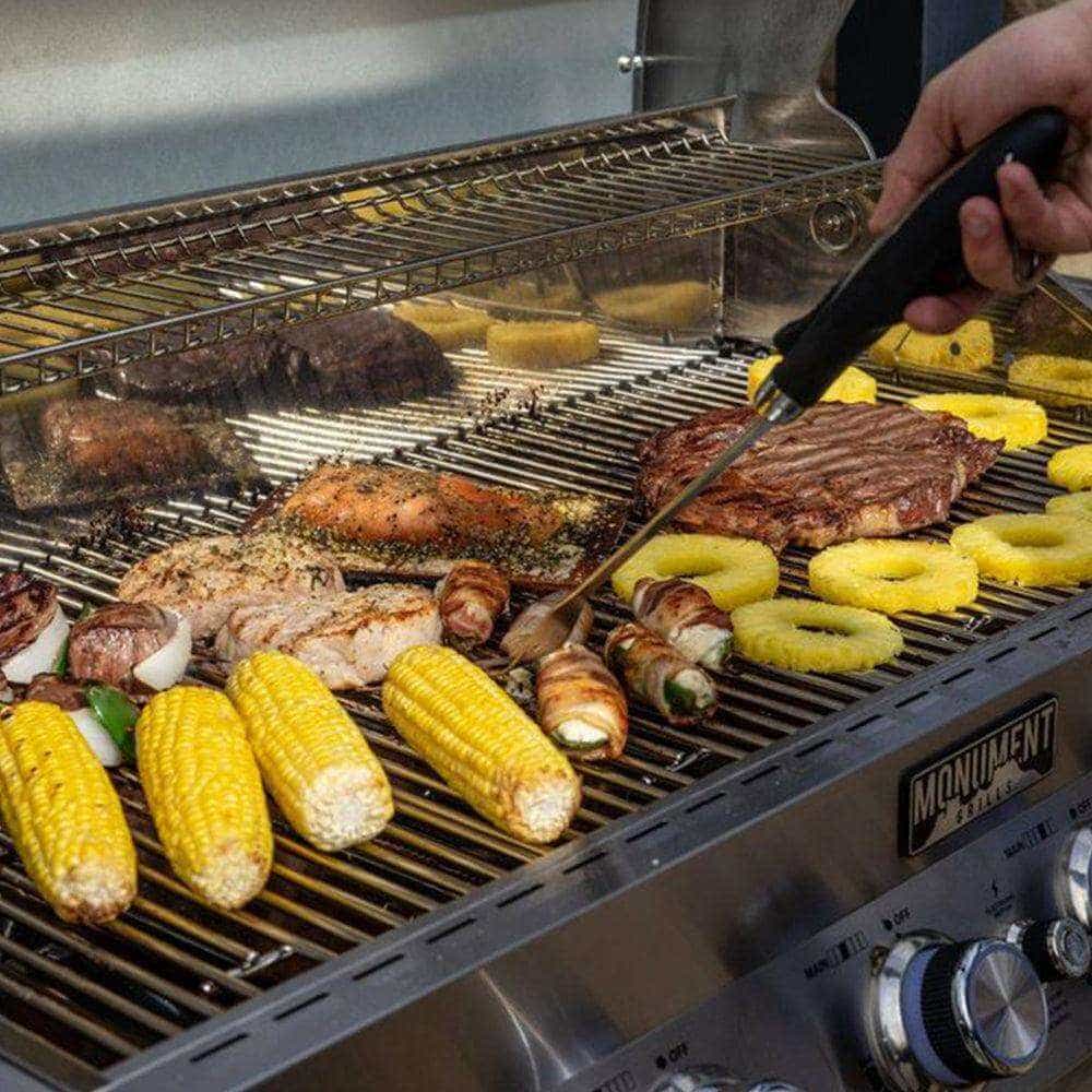 Grilling scene with various meats and vegetables on a barbecue, including corn and pineapple rings.