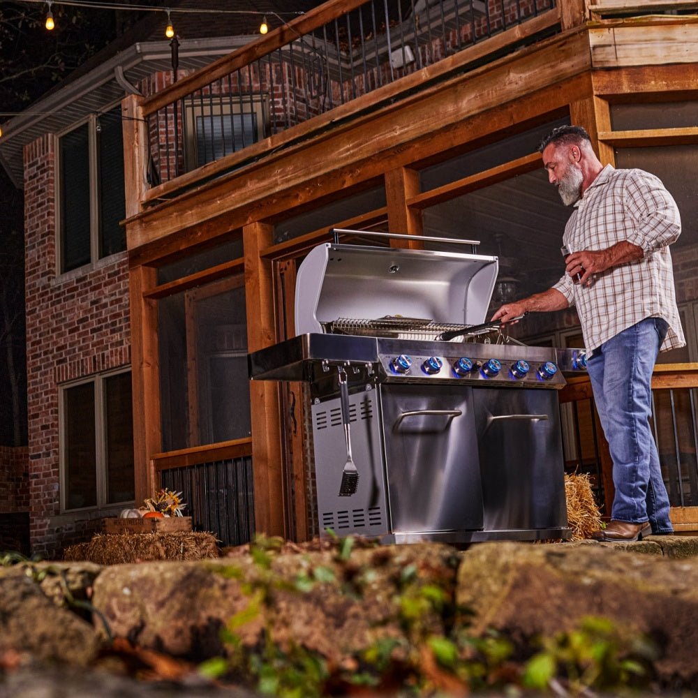 Man using a large outdoor grill in a backyard setting
