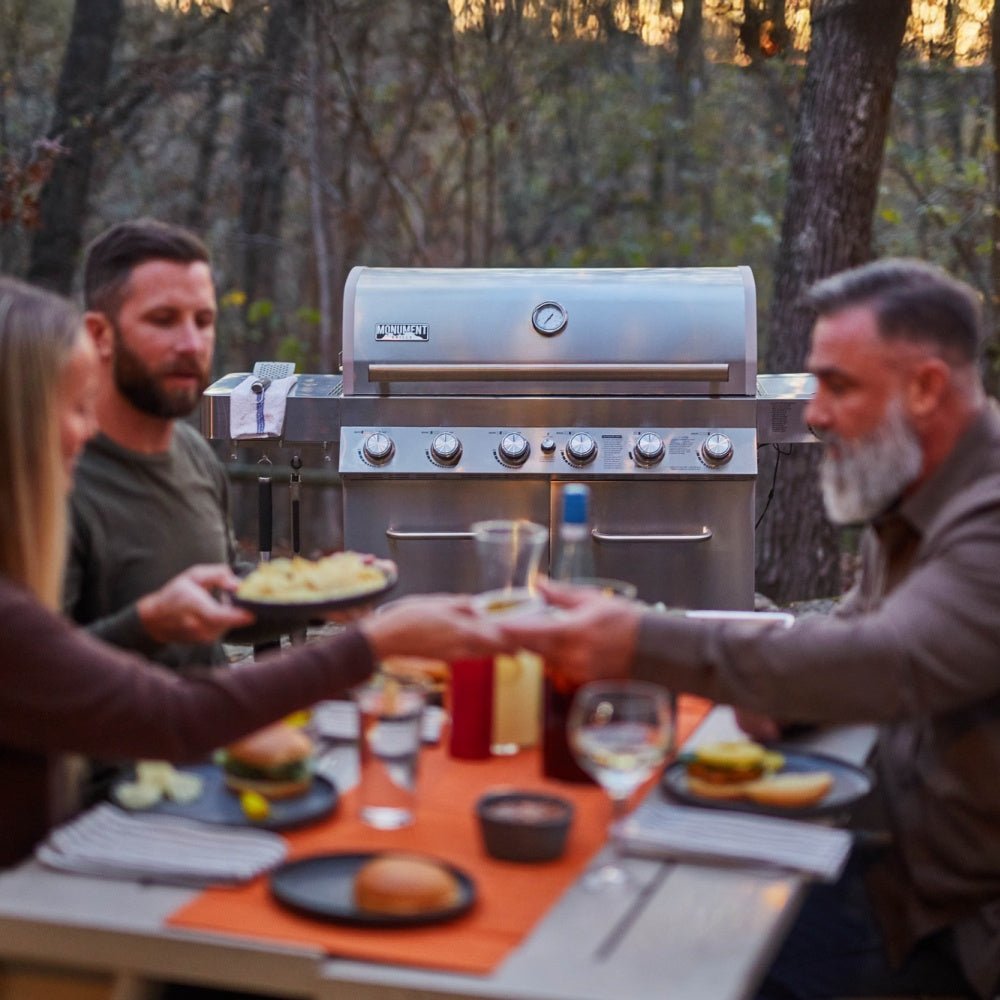 Group of people enjoying a meal around a grill in a forest setting