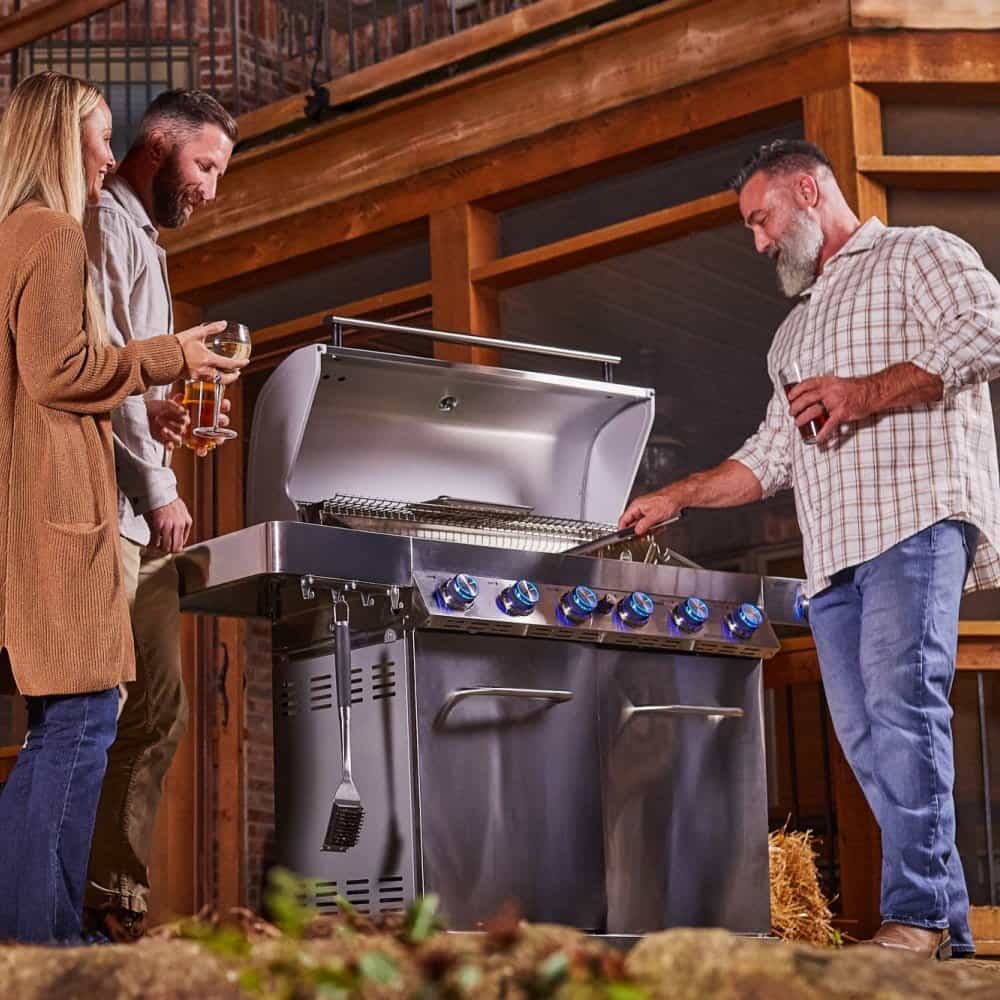 Two people standing next to a large barbecue grill in an outdoor setting.