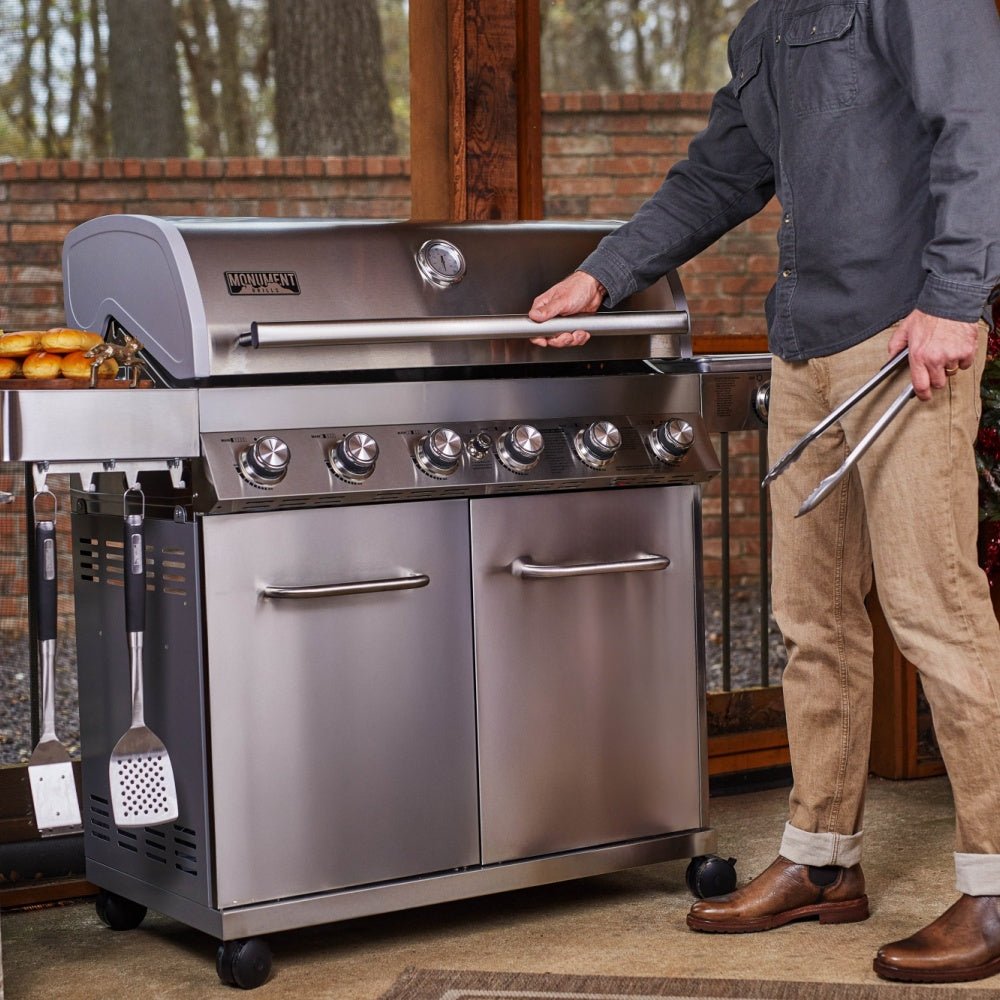 Stainless steel grill with a person interacting with it outdoors.