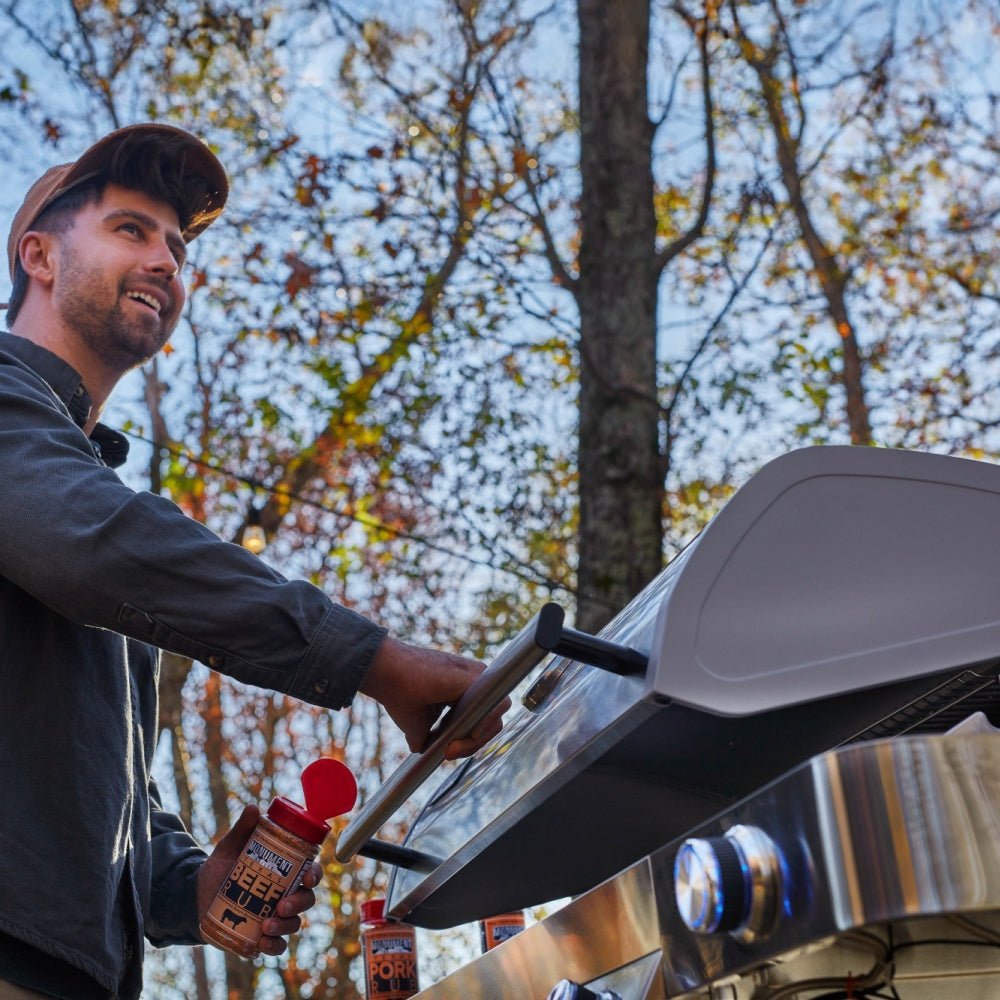 Man grilling outdoors with trees in the background