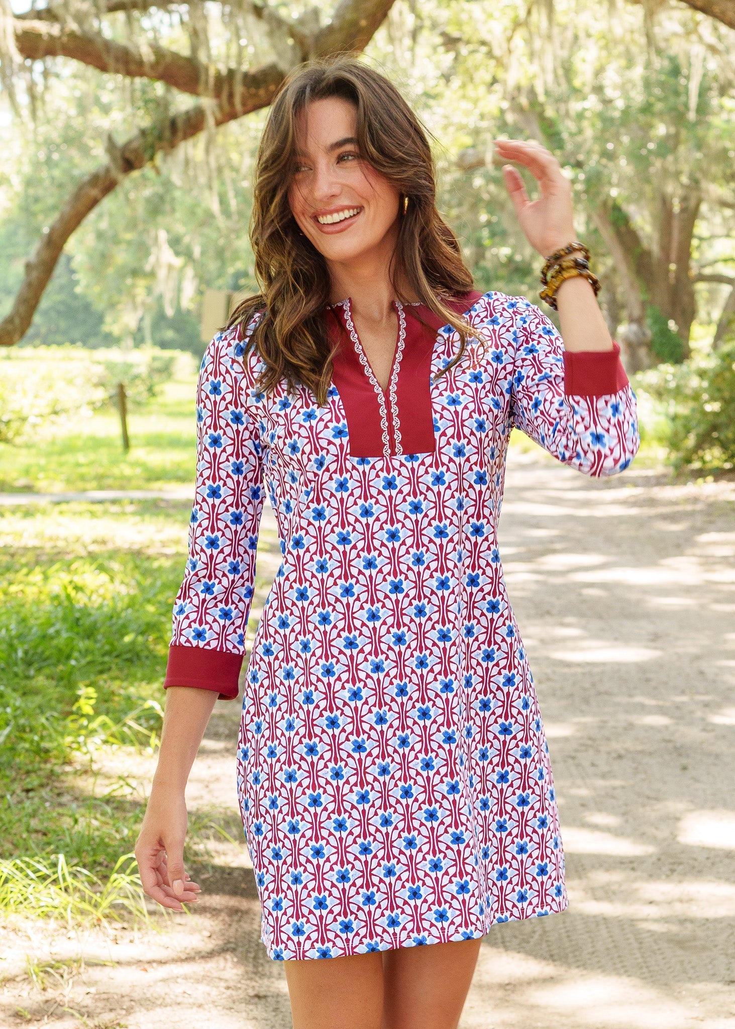 Woman wearing a patterned dress with red and blue design outdoors.