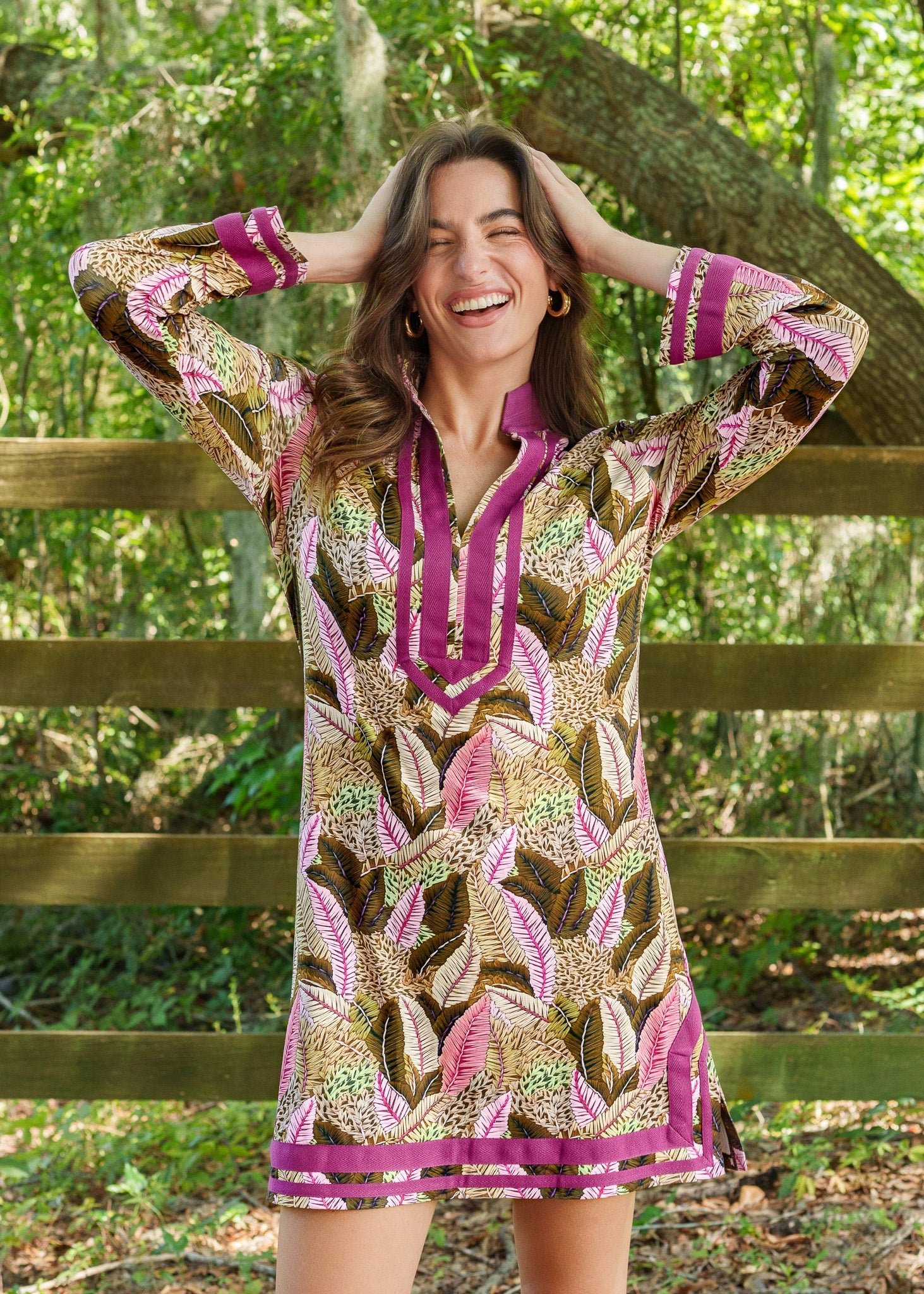 Woman wearing a patterned dress with purple accents standing in a forest setting.