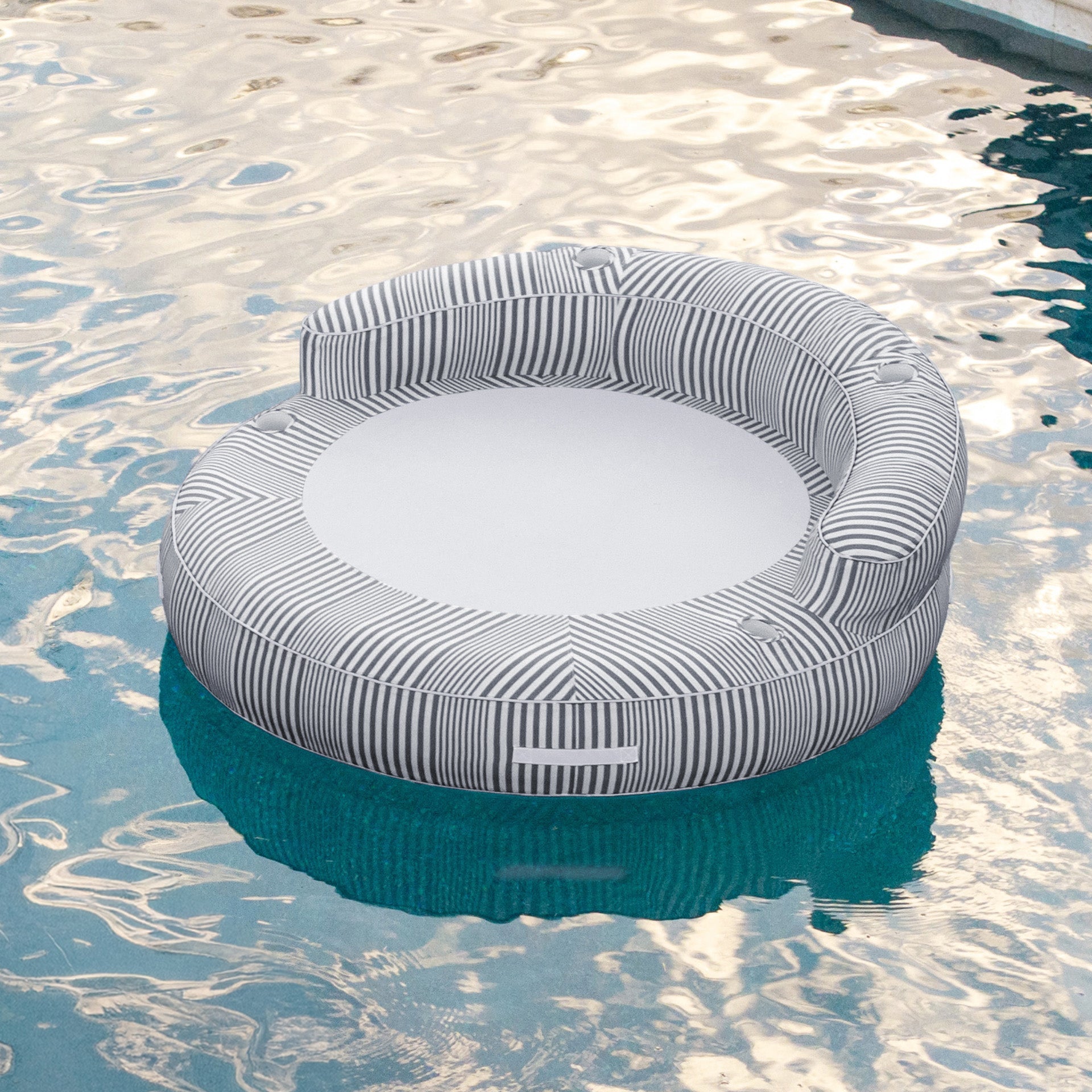 Round inflatable pool float with striped pattern floating on water