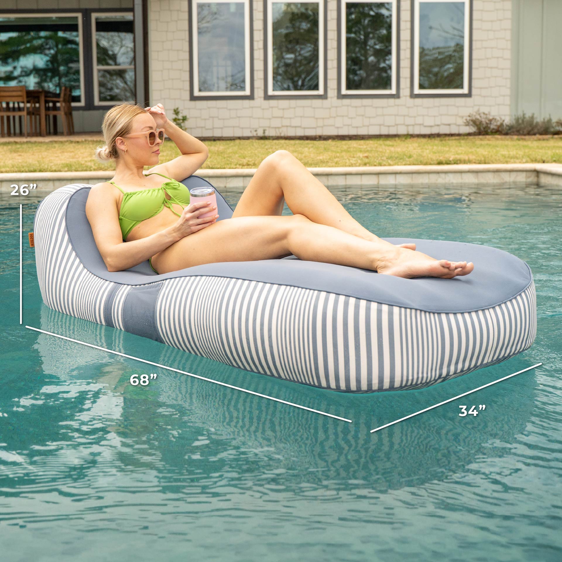 Woman lounging on a striped pool float in a pool with measurements displayed