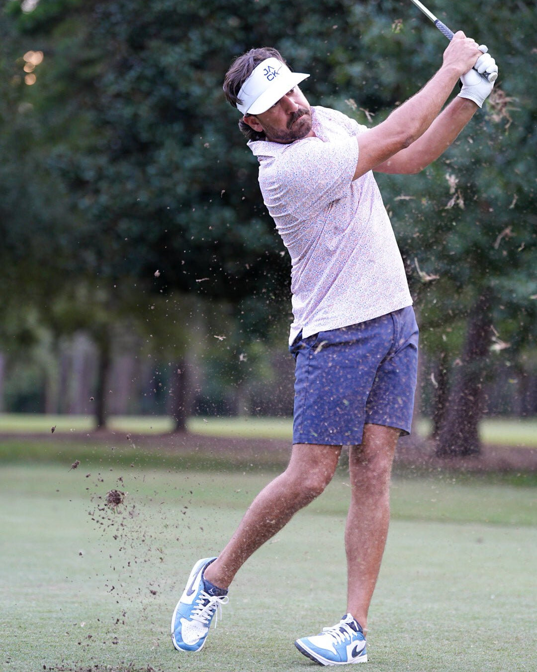 Golfer in action on a golf course with trees in the background