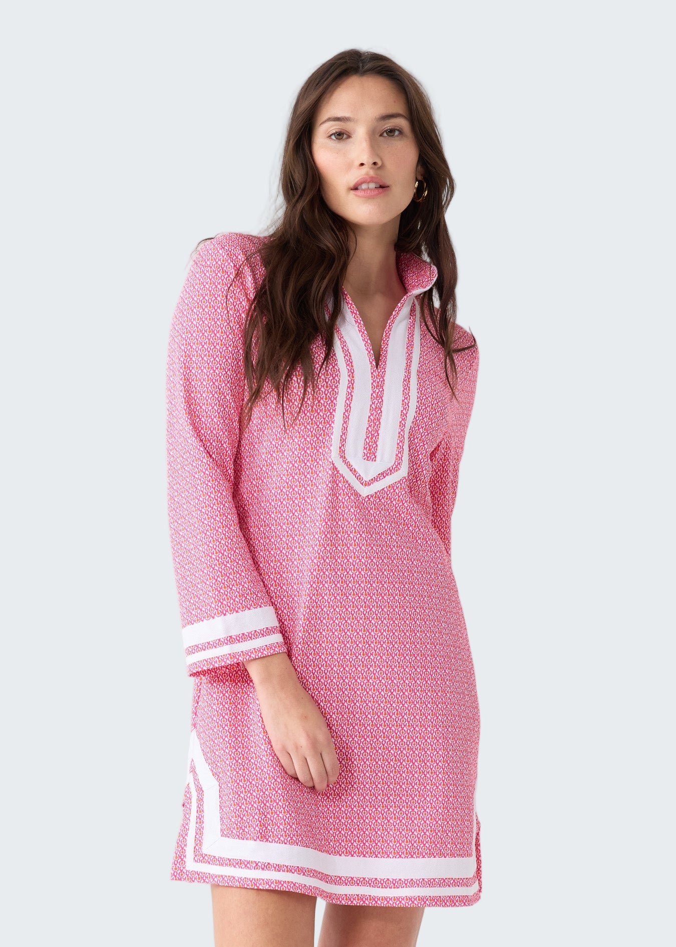 Woman wearing a pink dress with white accents on a white background