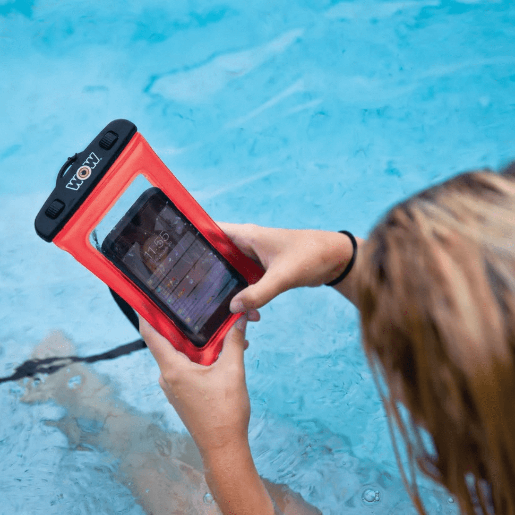 Person holding a phone in a red waterproof case by a pool
