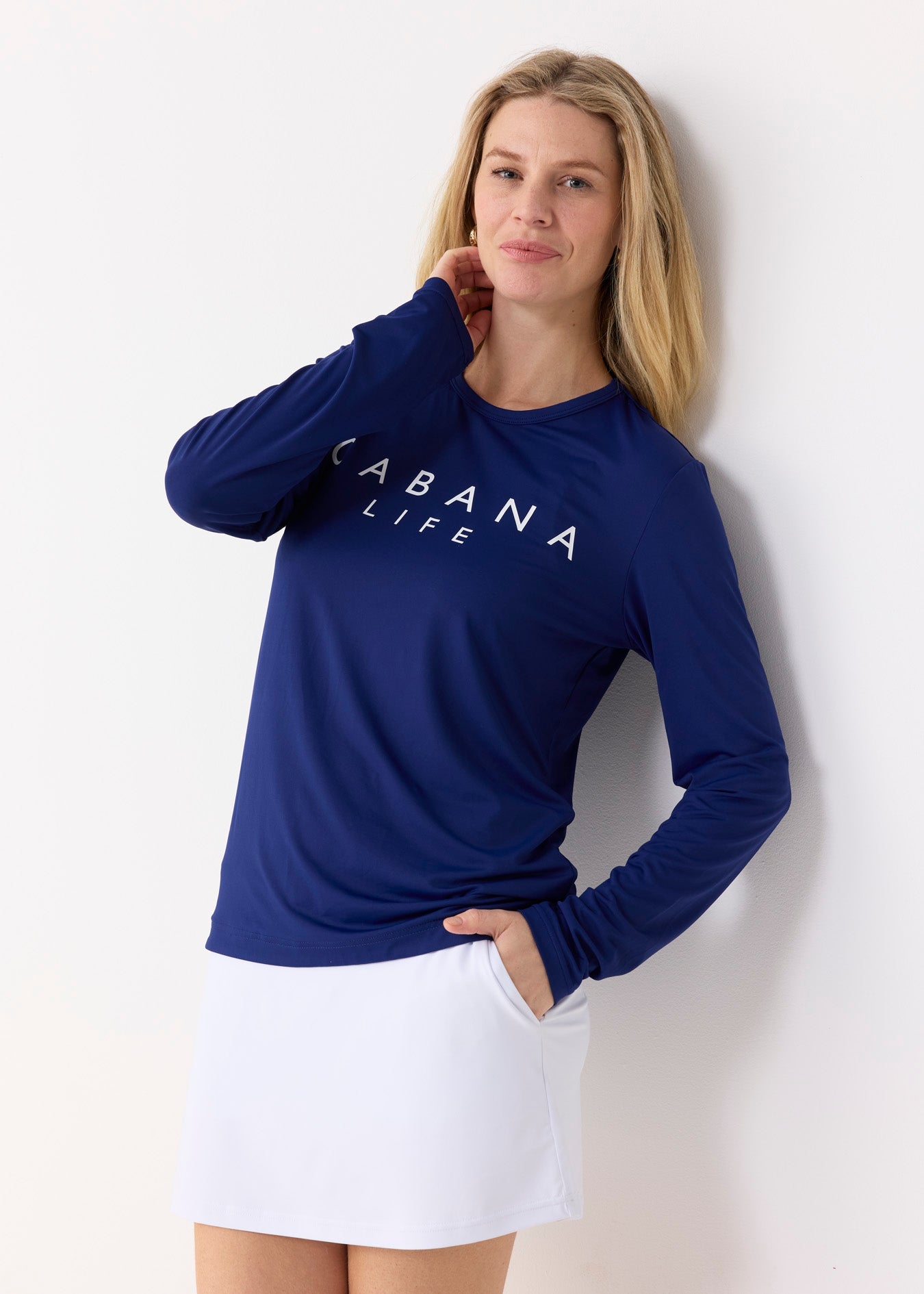 Woman wearing a blue 'Cabana Life' shirt and white skirt against a white background