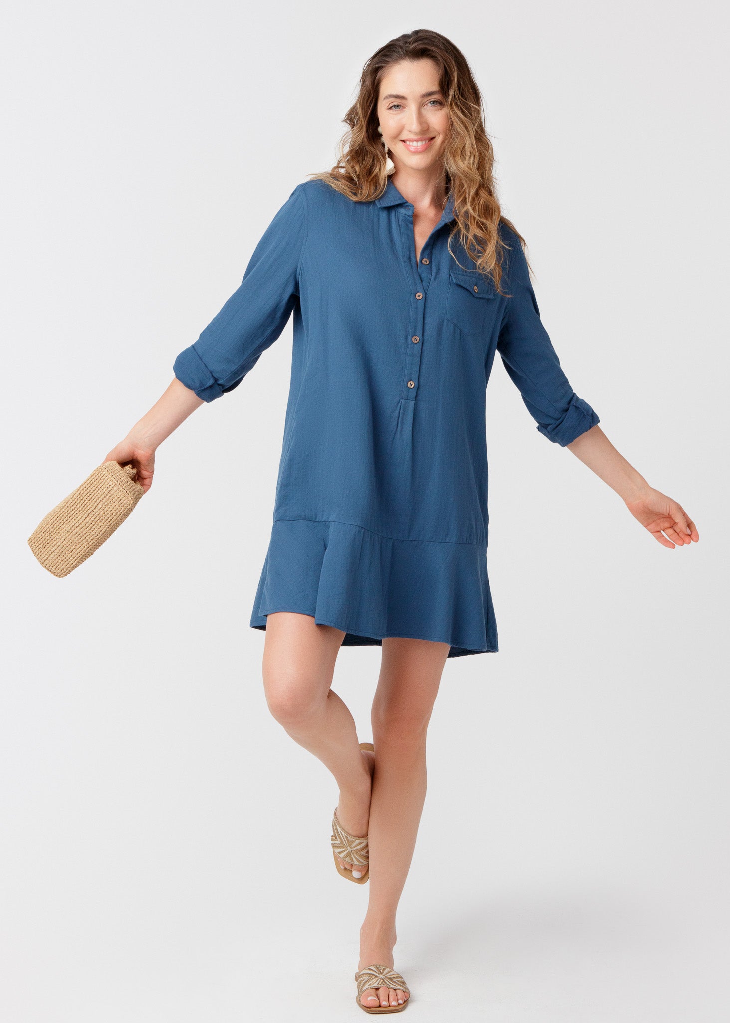 Woman wearing a blue dress holding a straw bag on a white background